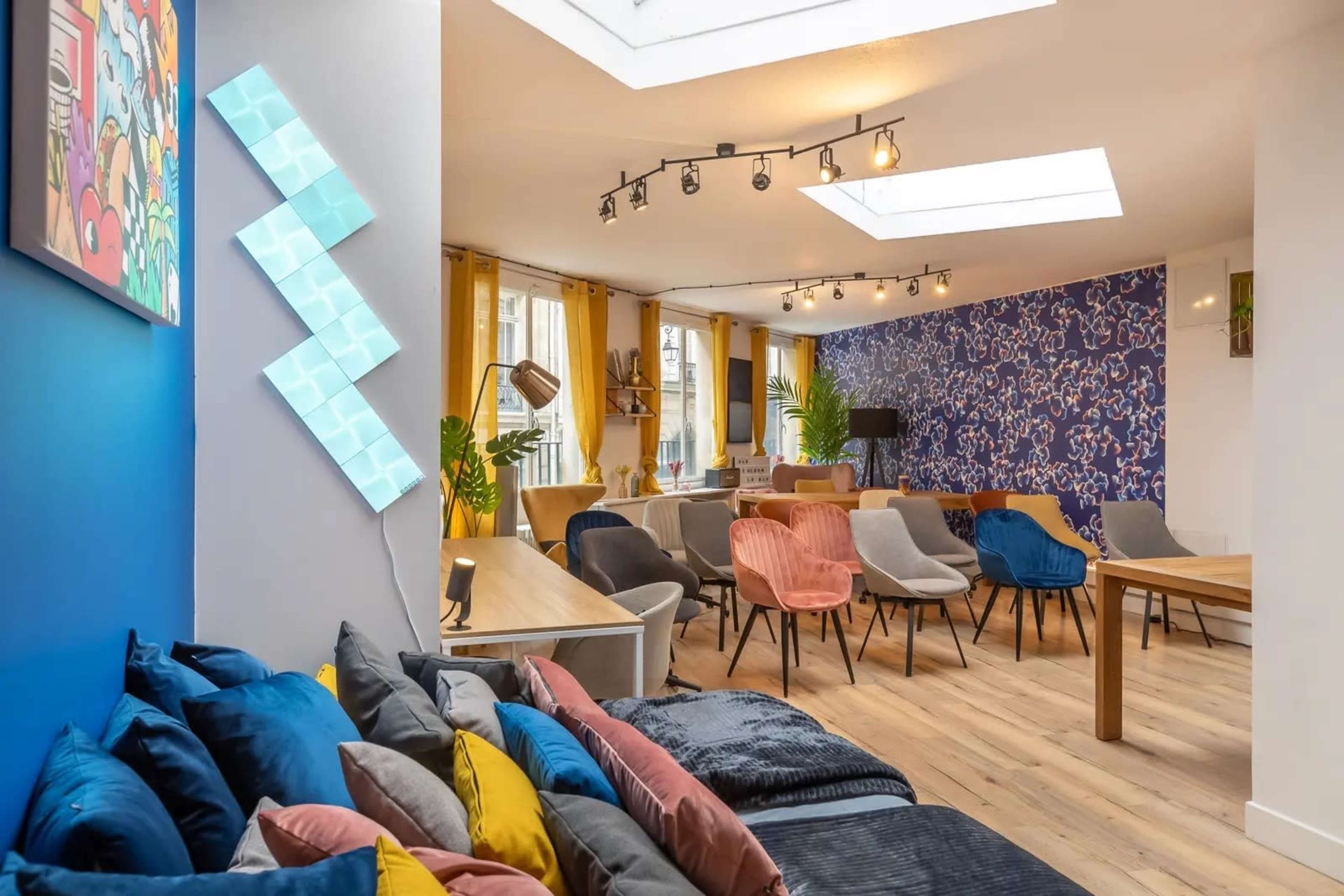 The image shows a modern, open interior space with colorful seating, a skylight, and decorative wall panels.