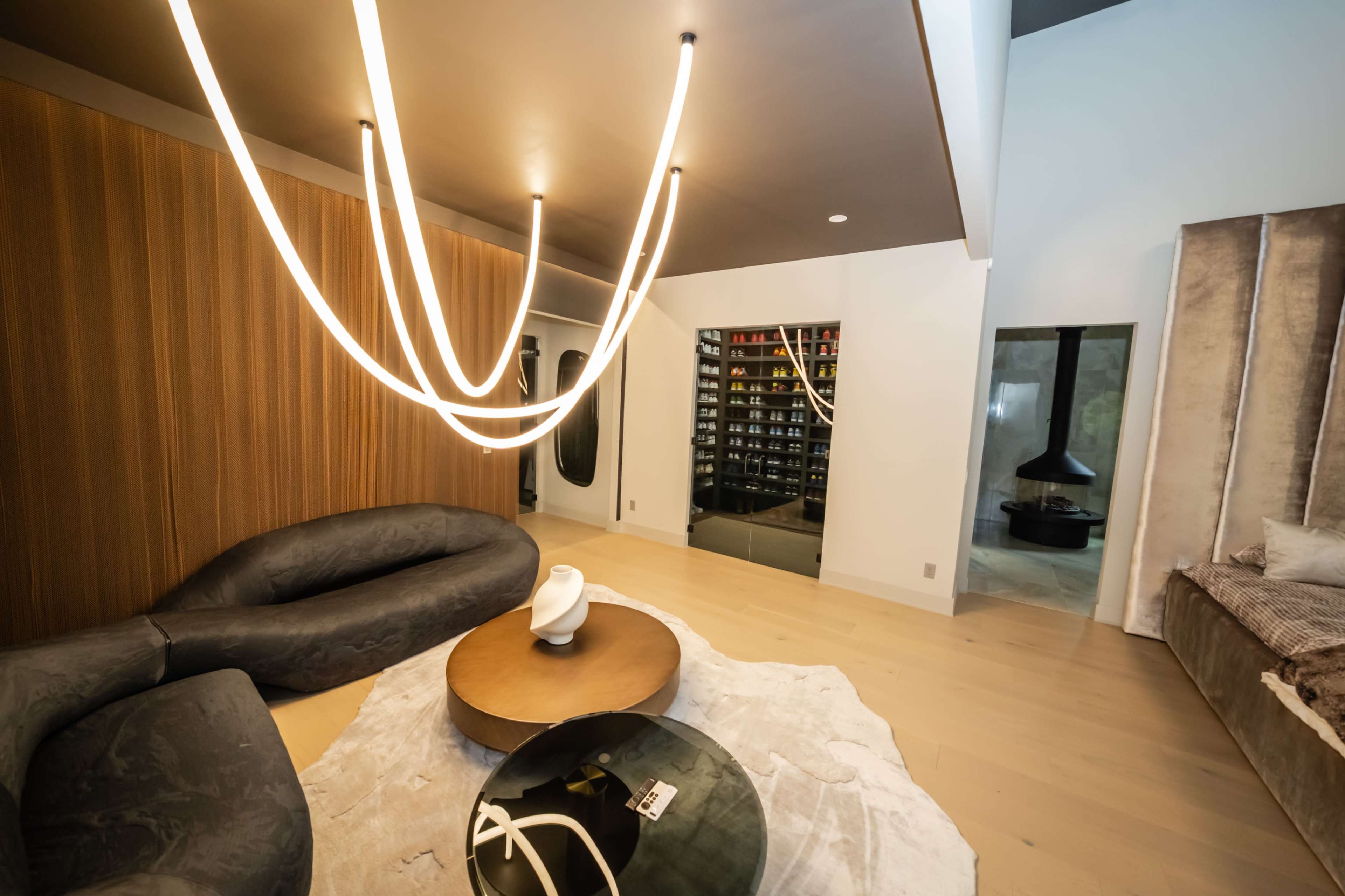 The image shows a modern, stylish interior featuring a lounge area with a curved sofa, a round coffee table, and a wine wall in the background.