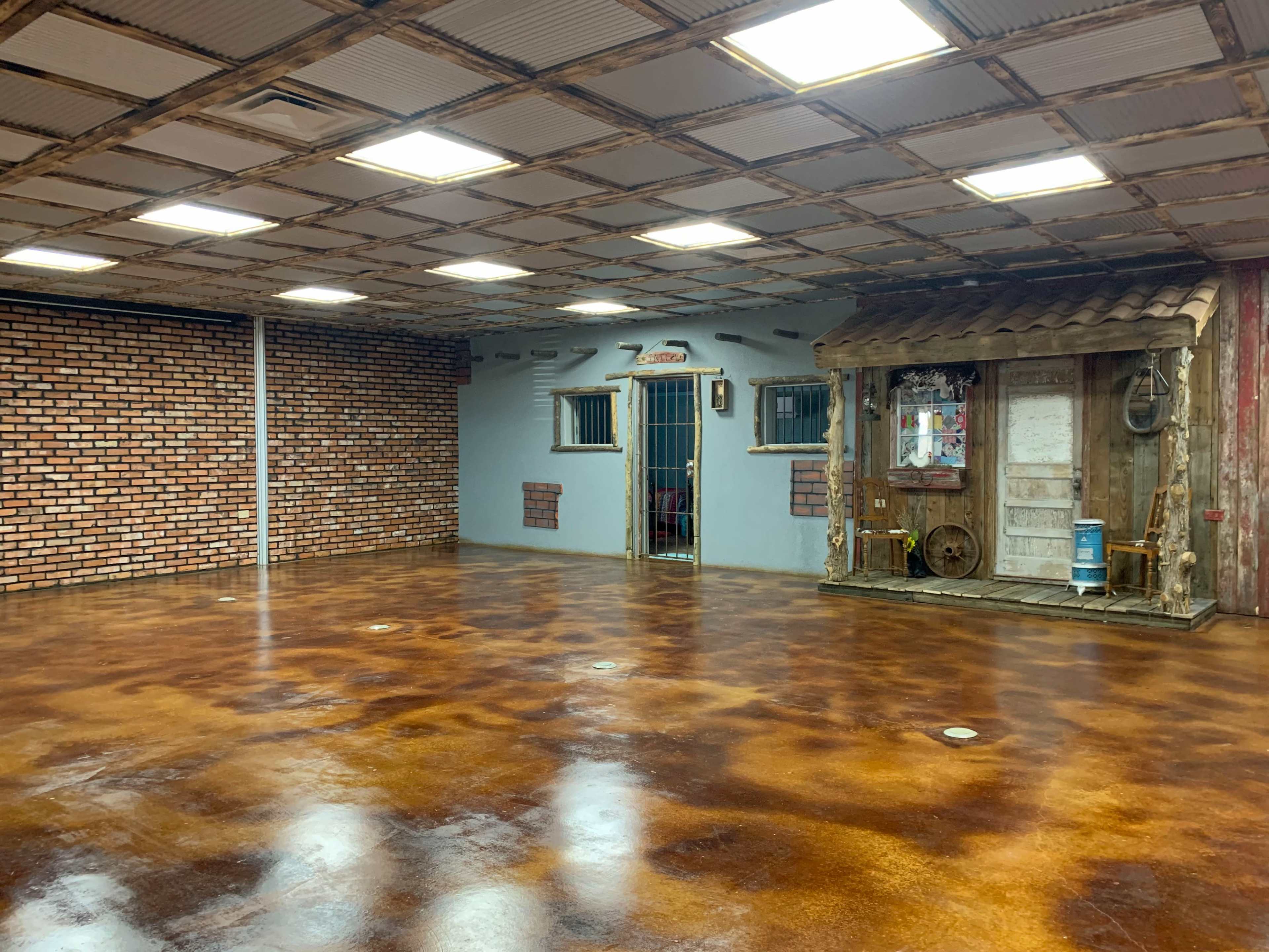 A spacious interior with a polished concrete floor, a brick-patterned wall, and a wooden-themed structure on one side.