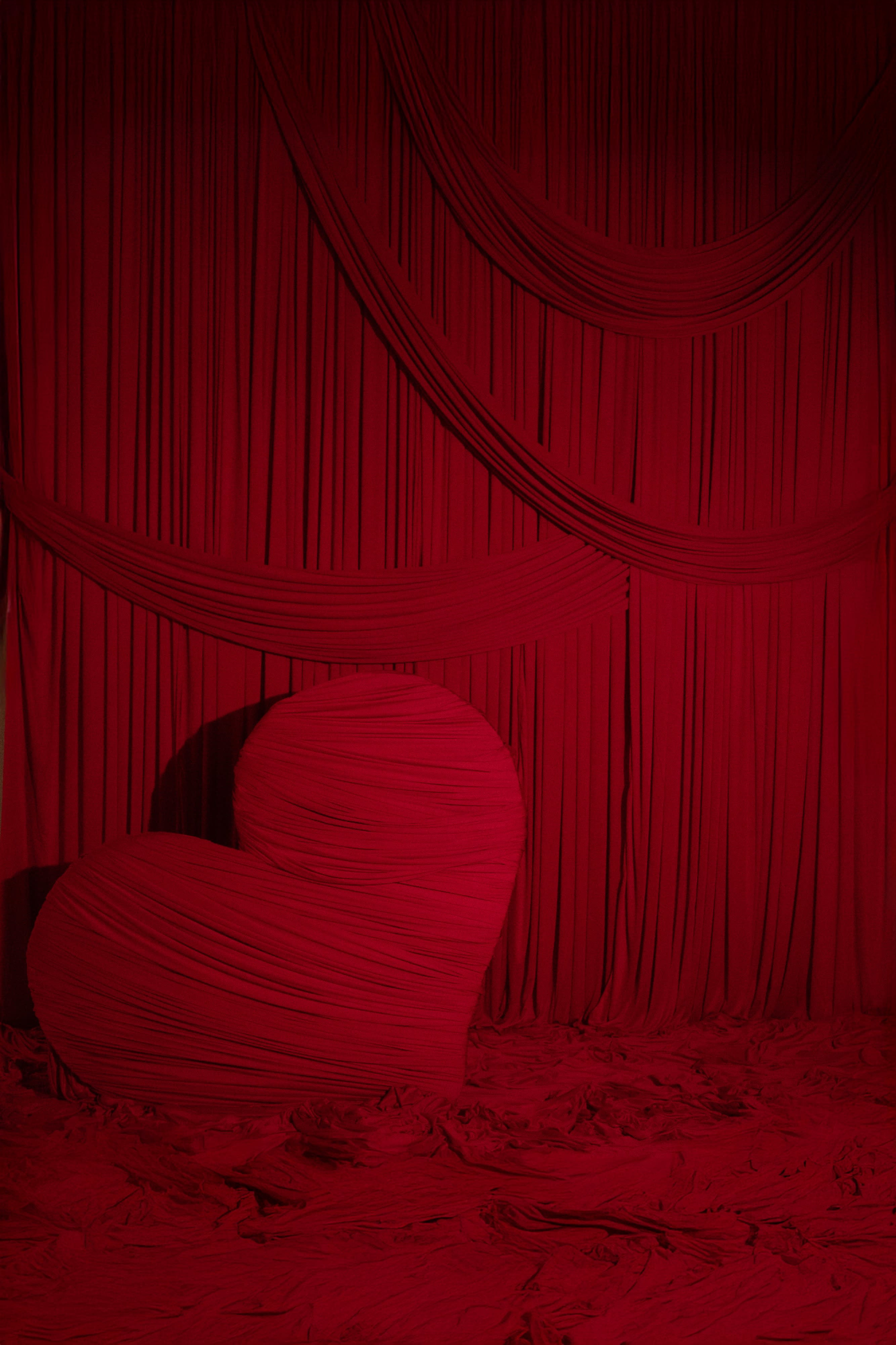 The image features a large, textured red heart against a backdrop of flowing red fabric.