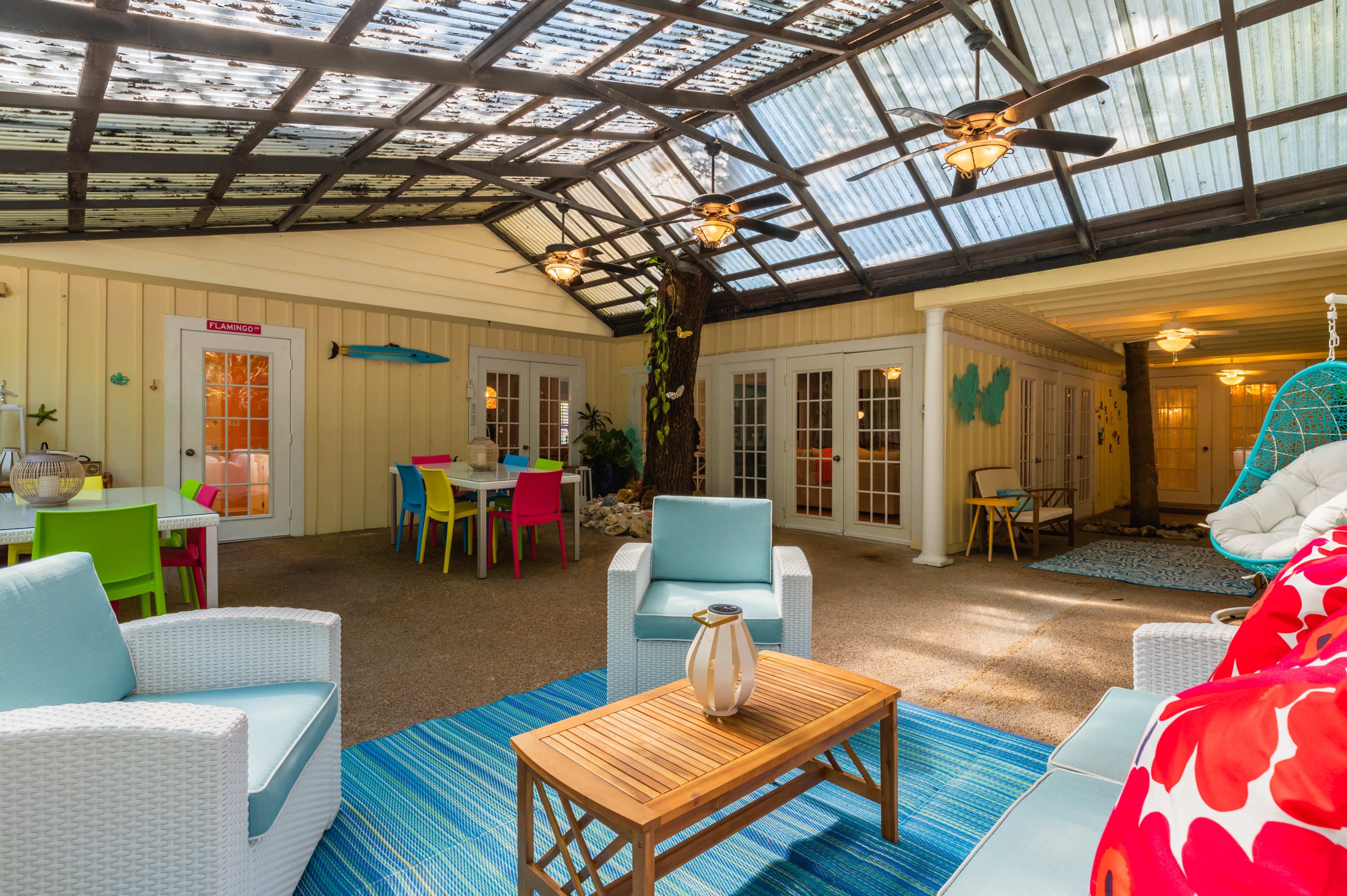 A bright indoor space with a glass roof, featuring comfortable seating, colorful chairs, and vibrant decor.