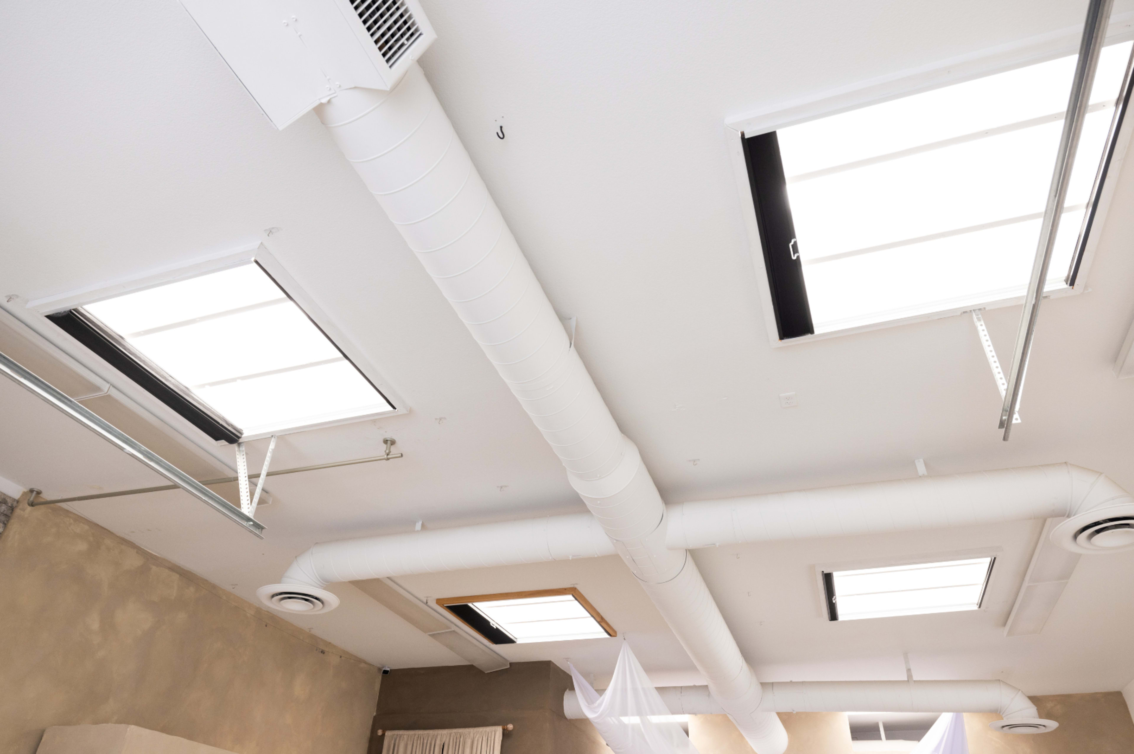 A ceiling with exposed air ducts and skylights.