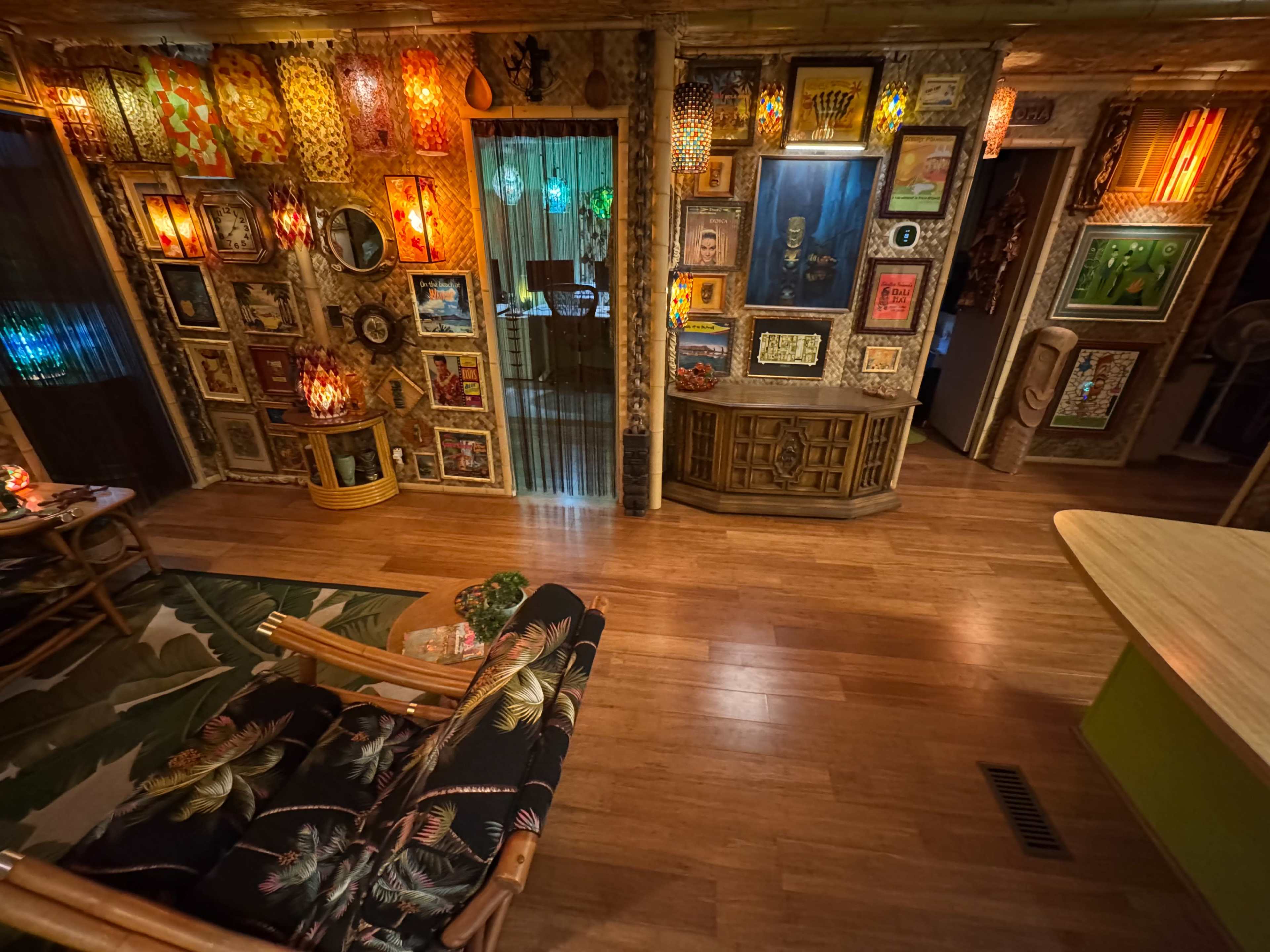 The room features wooden flooring and walls adorned with colorful framed artwork and various lanterns, creating a vibrant and eclectic atmosphere.