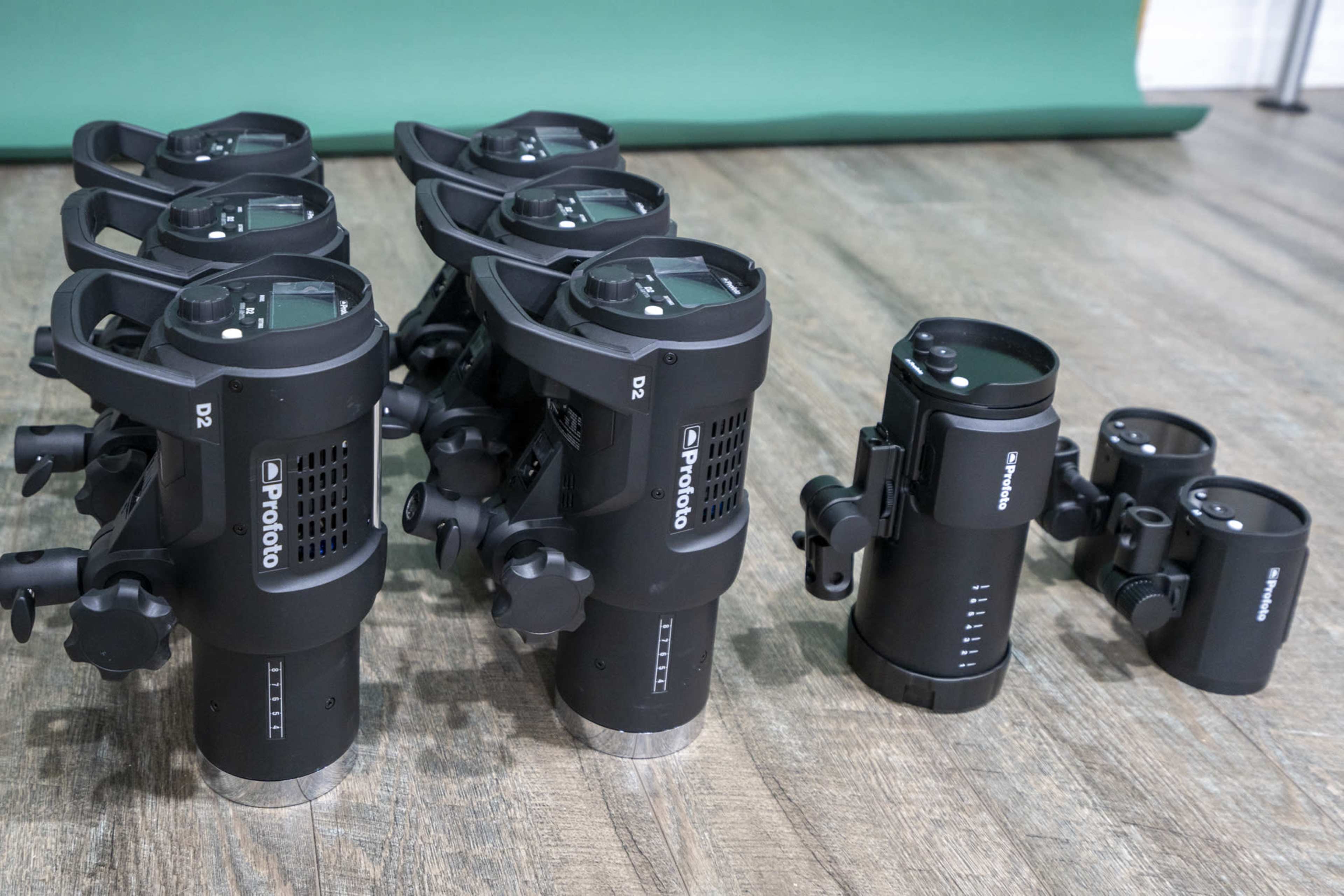 A lineup of six Profoto D2 studio flash units arranged beside a smaller light accessory.