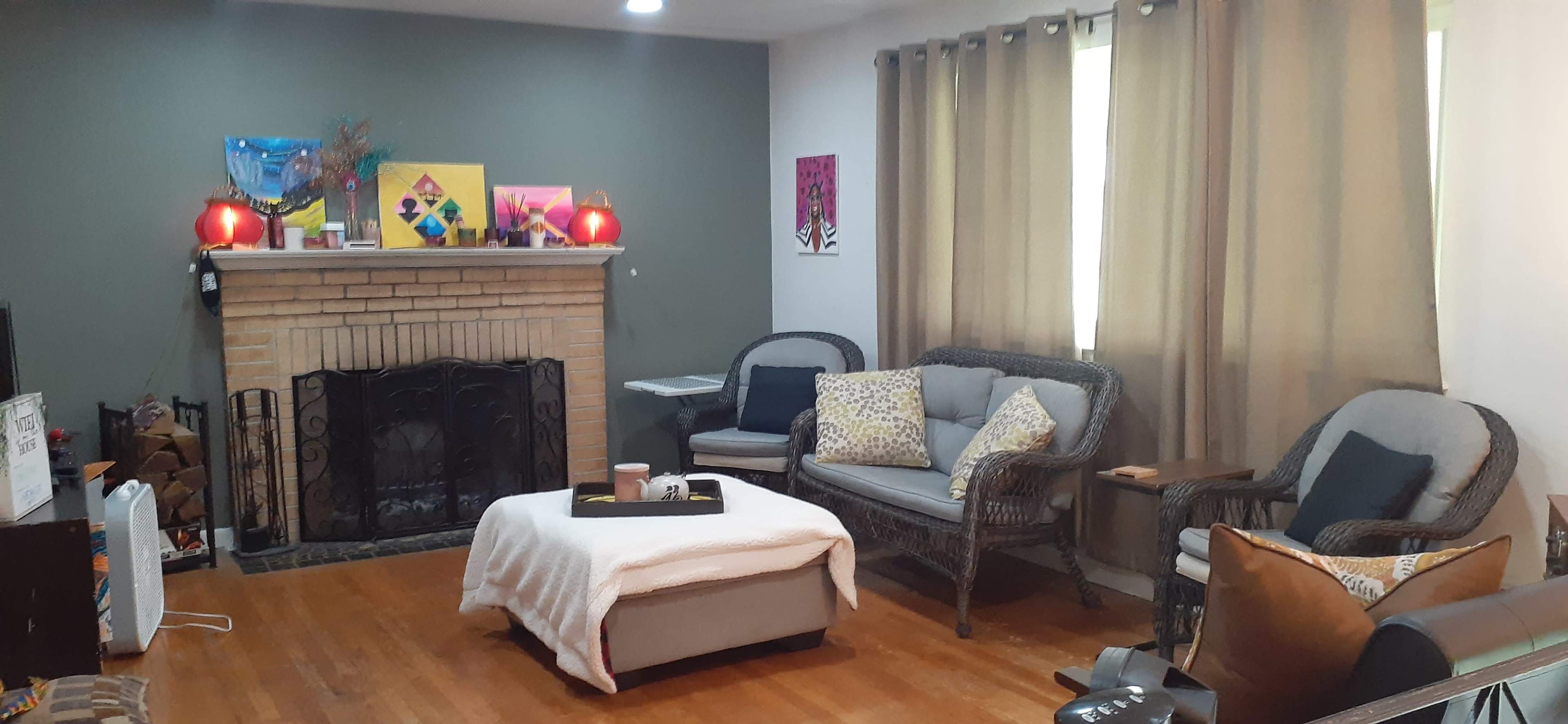 A living room with a fireplace, two couches, a coffee table, and artwork displayed on the walls.