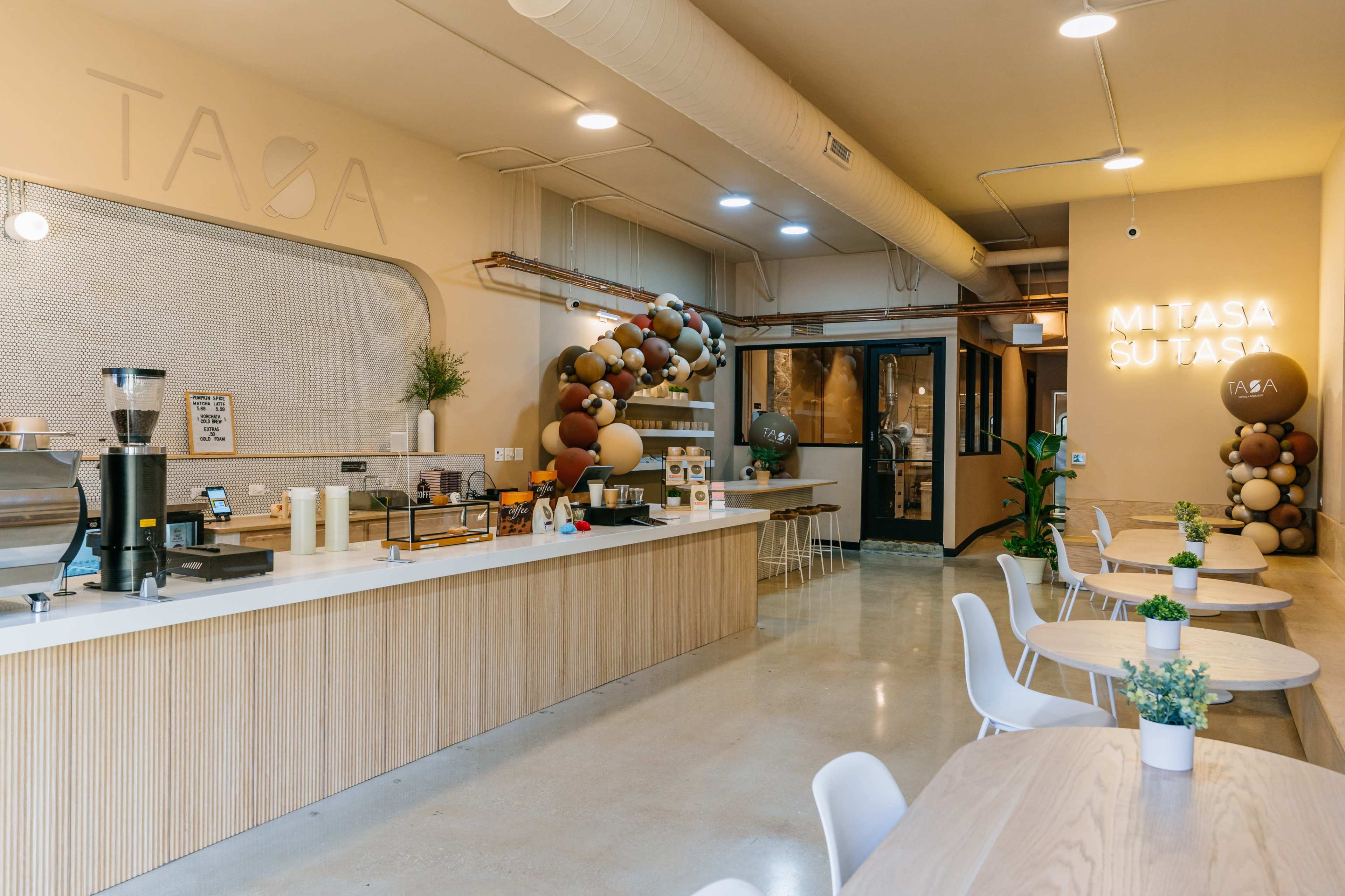 The image shows a modern café interior with a long countertop, seating areas, and decorative balloon arrangements.