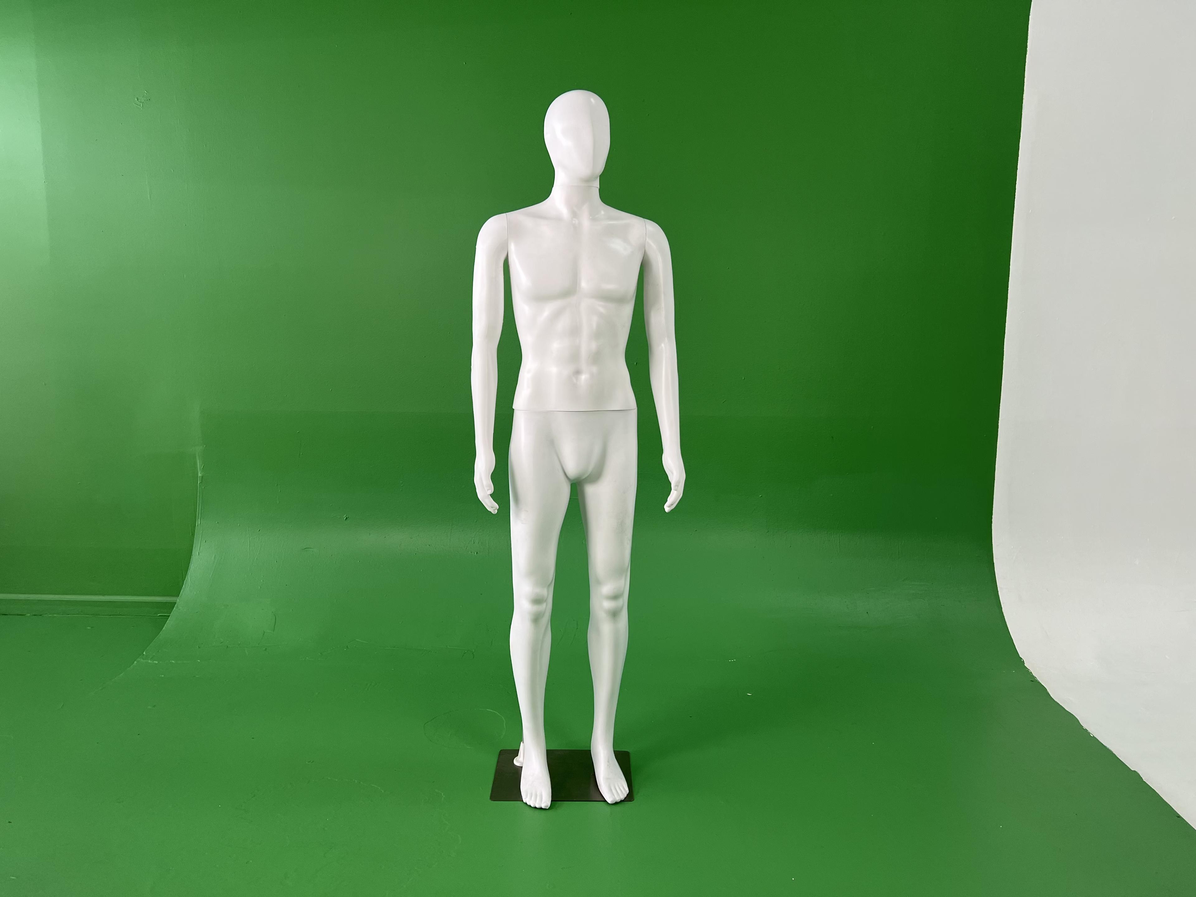 A white mannequin stands upright on a black base in front of a green backdrop.
