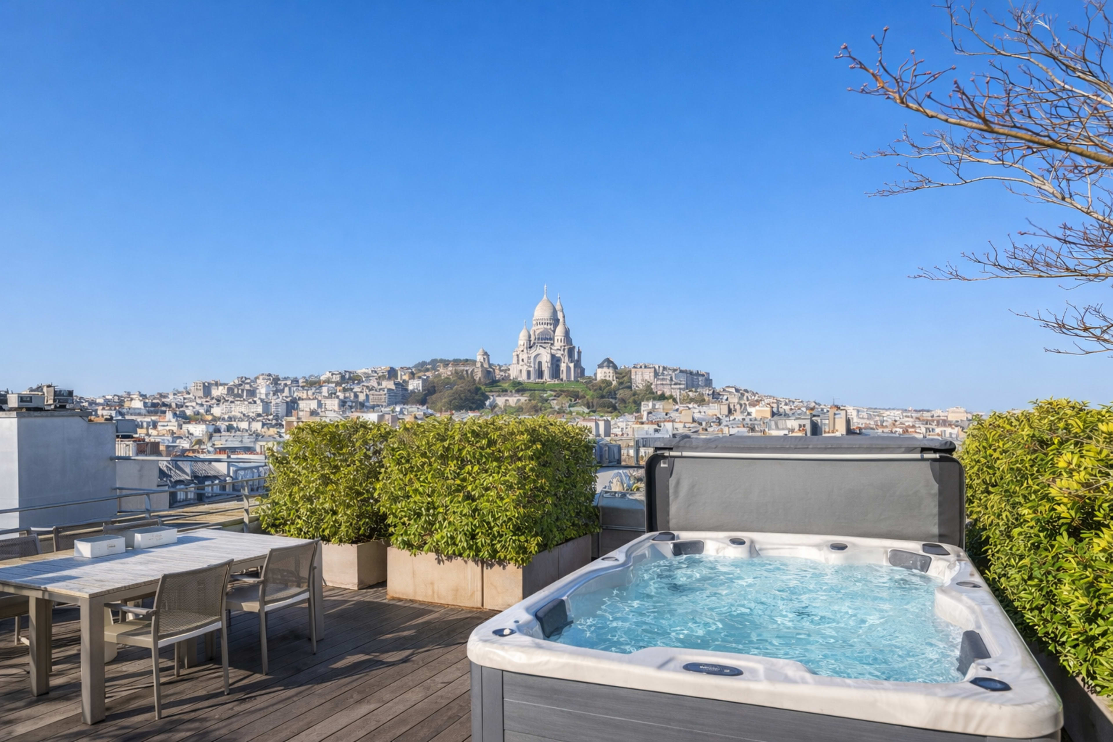 The image shows a rooftop terrace in Paris featuring a hot tub, outdoor dining table, and a view of the Sacré-Cœur Basilica on a clear day.