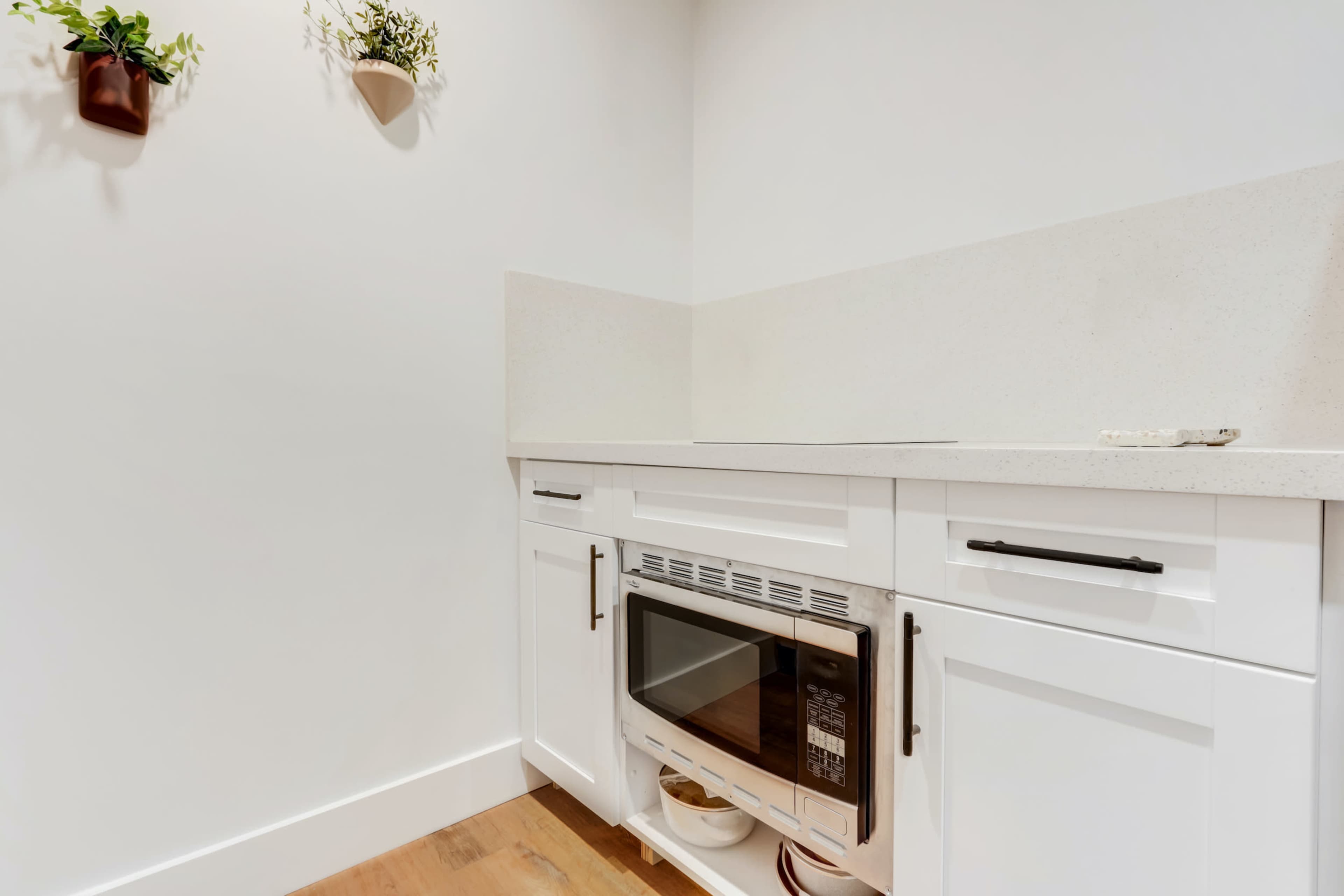 A corner of a kitchen with white cabinetry, a countertop, and a built-in microwave.