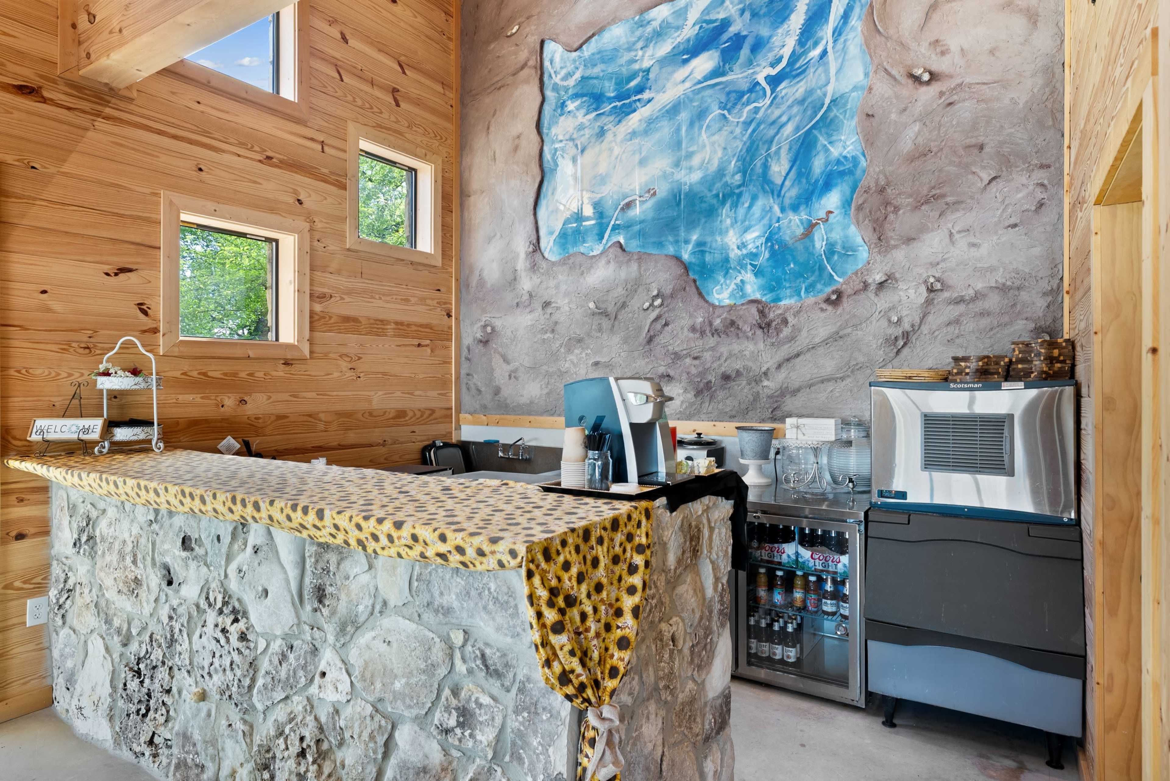 The image shows a modern reception area with a stone counter, wooden walls, and a large artistic mural featuring a blue abstract design.