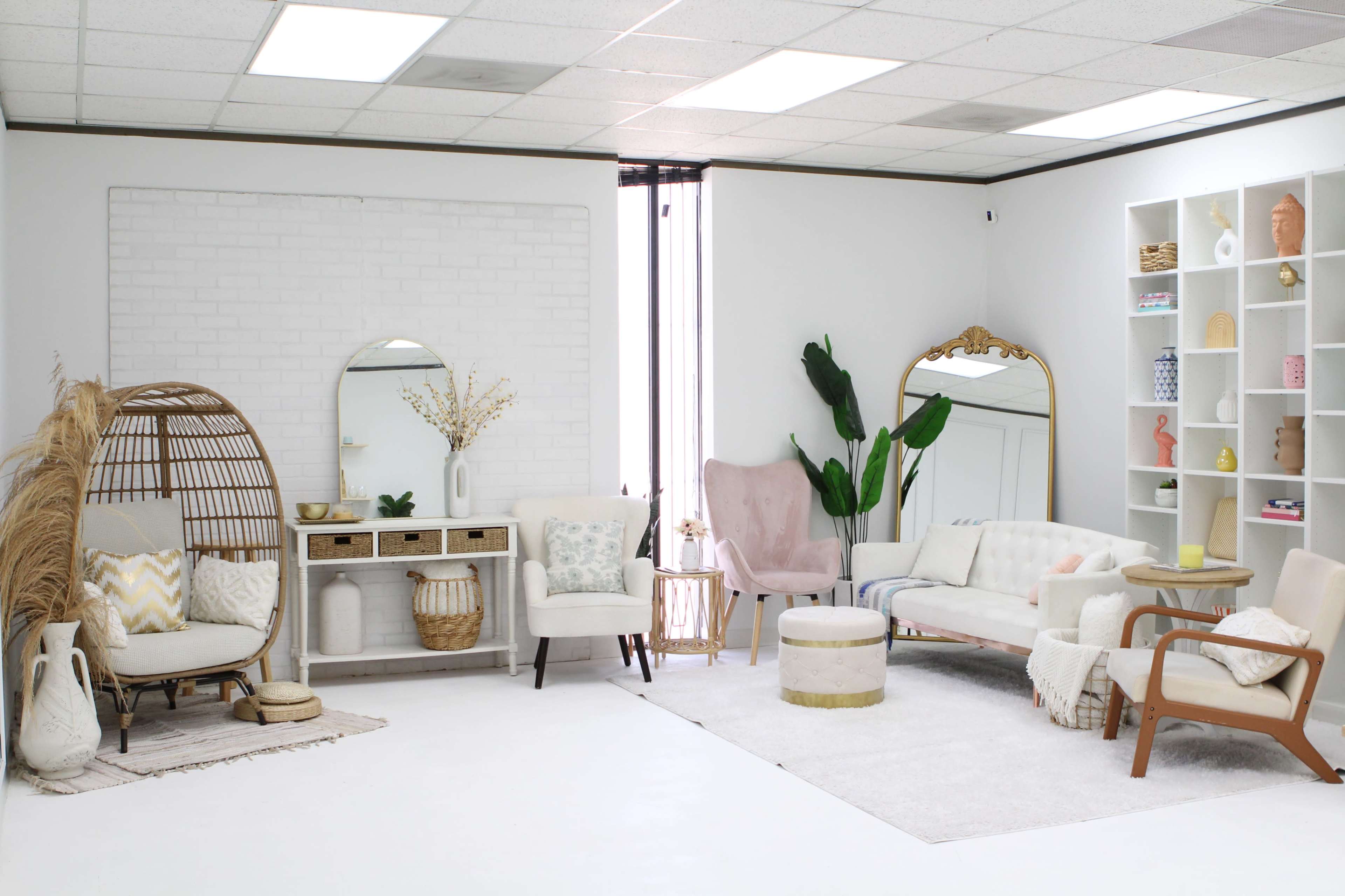 A bright, modern interior space featuring a variety of seating options, decorative furnishings, and shelving against a white wall.