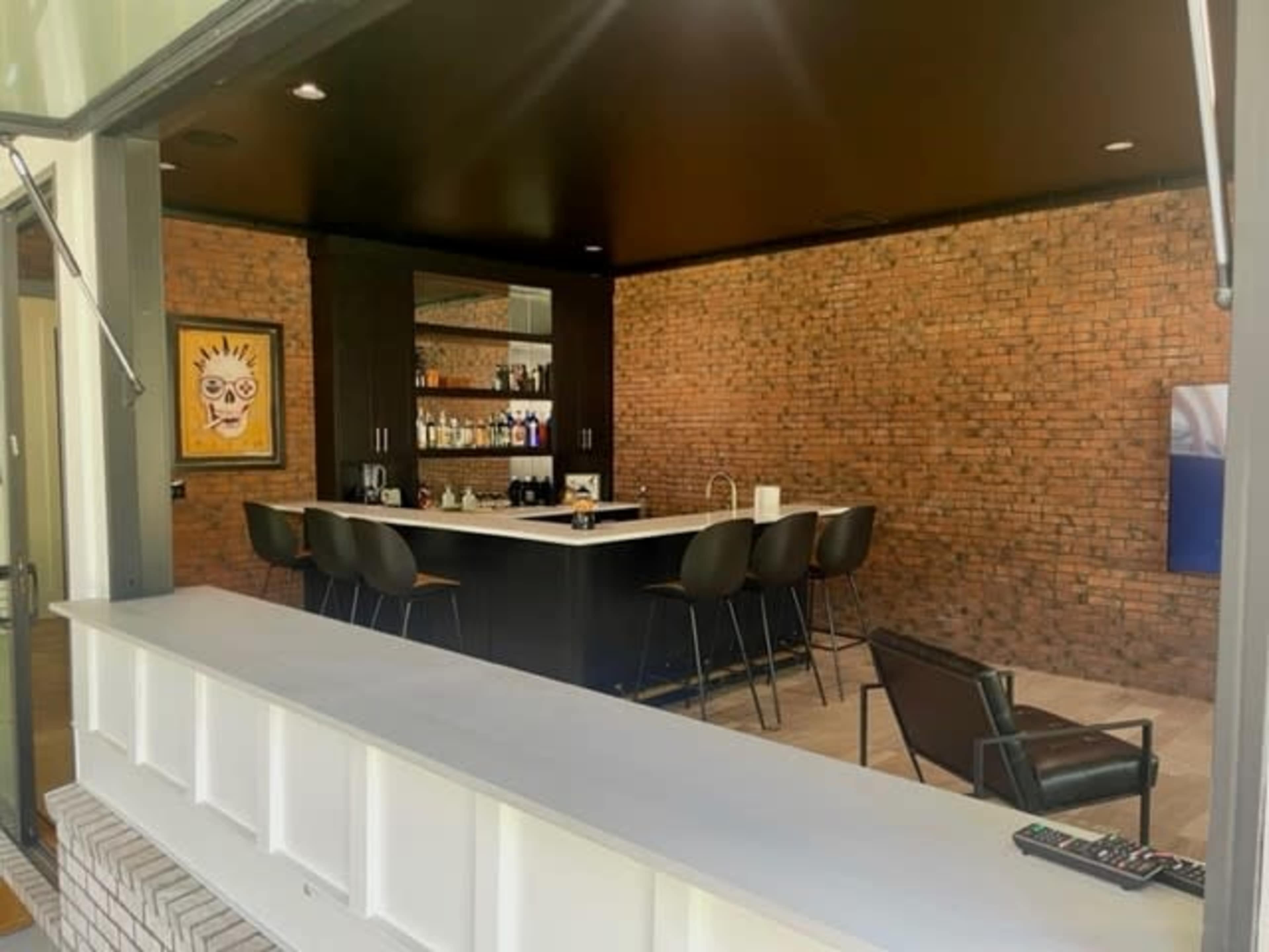 A modern bar area with a brick wall, a white countertop, and high stools.