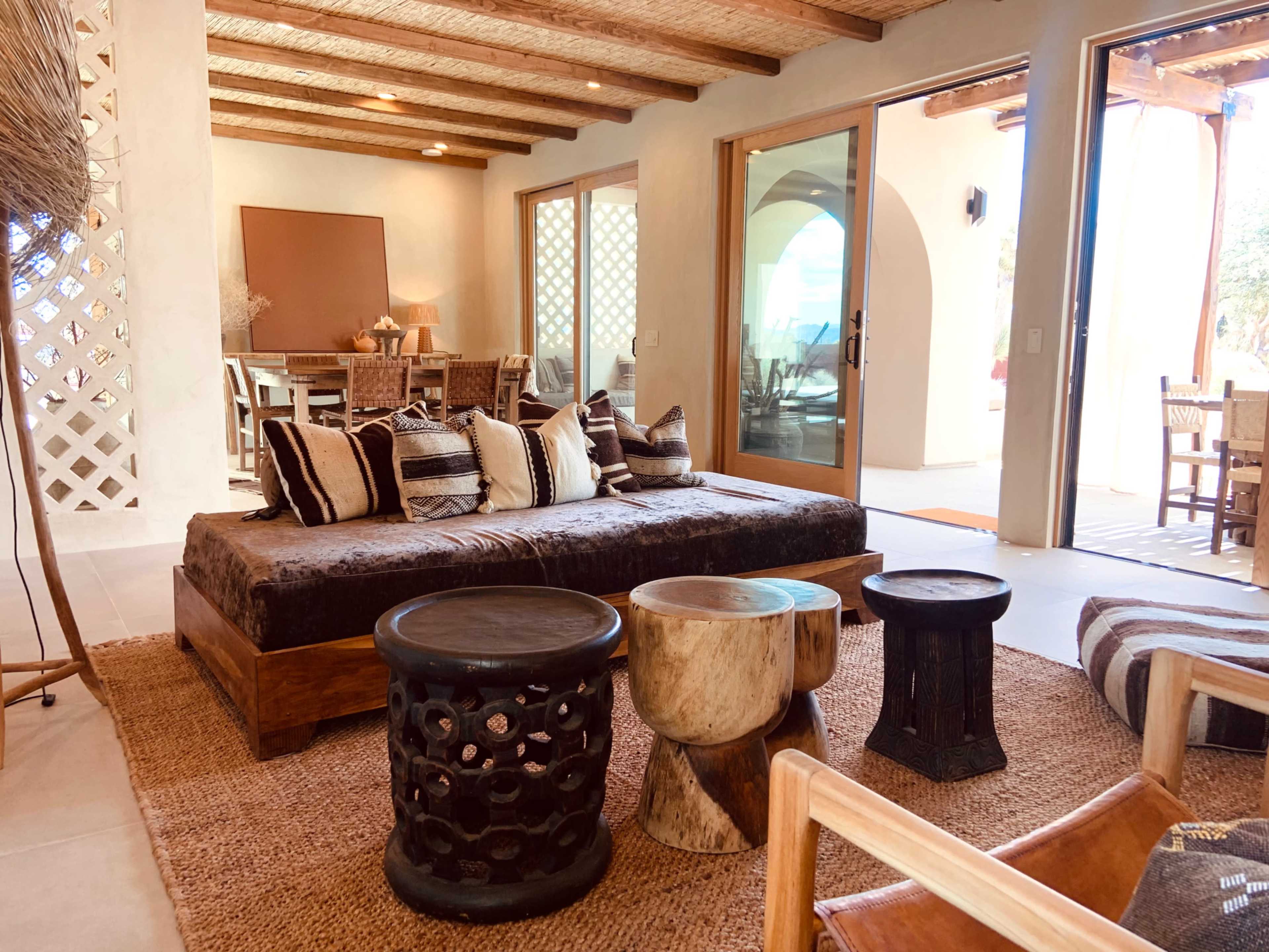 A spacious living area featuring a large wooden coffee table surrounded by various seating options and a dining area visible in the background.