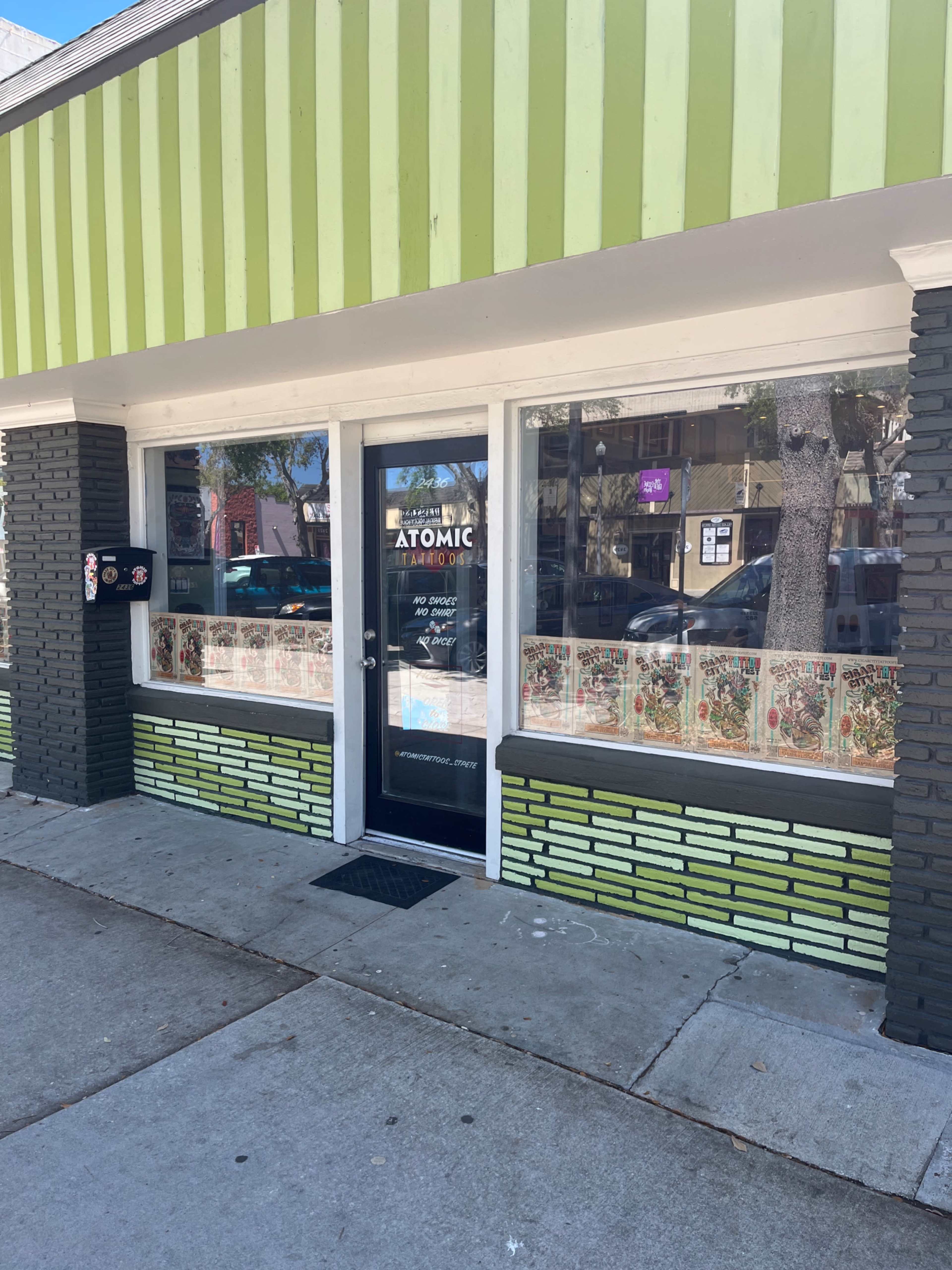 The storefront features a glass door with "Atomic" displayed prominently, surrounded by green and black striped exterior and patterned windows.