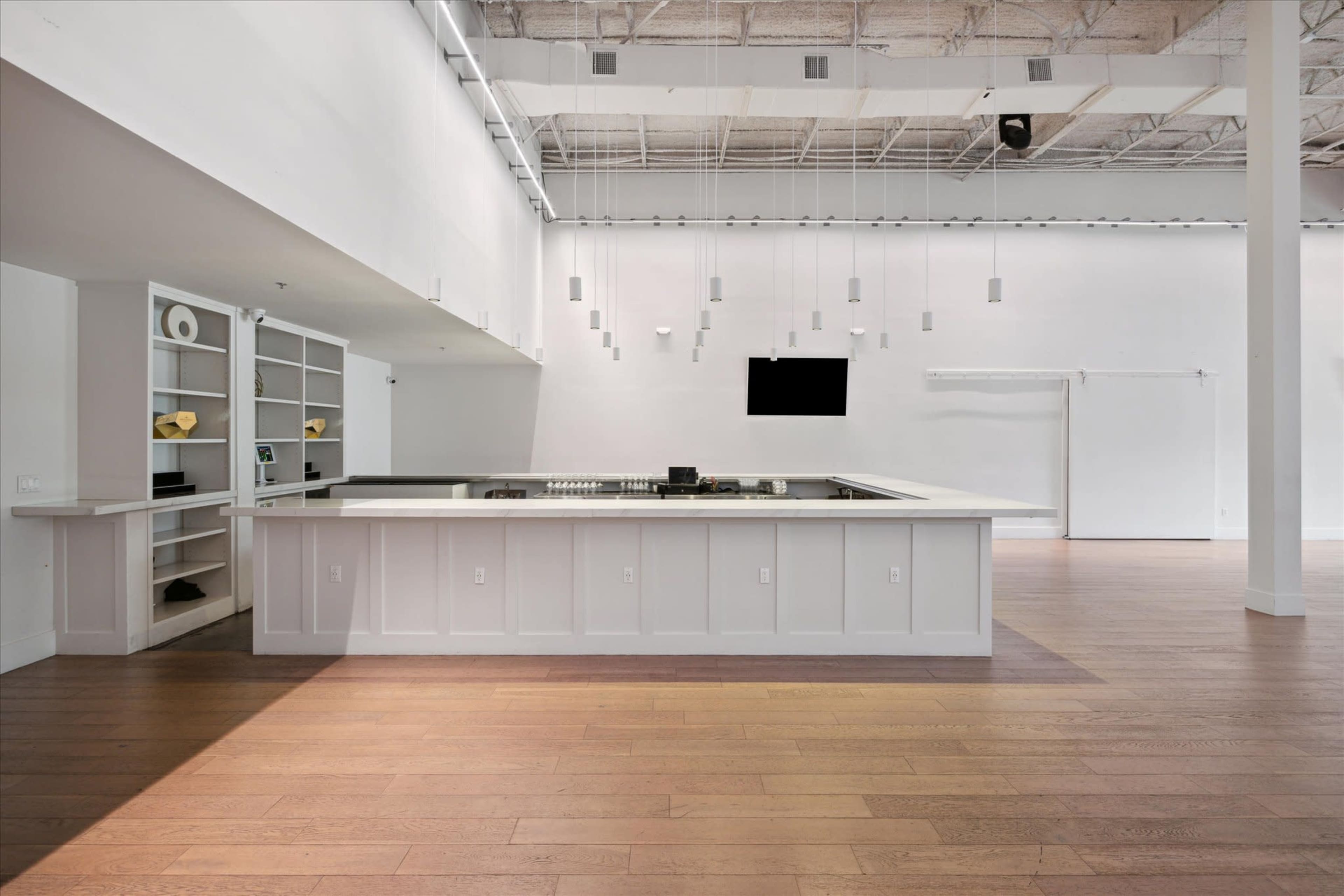 A spacious, modern kitchen area with an island and minimalistic design elements, set in a well-lit, open room.