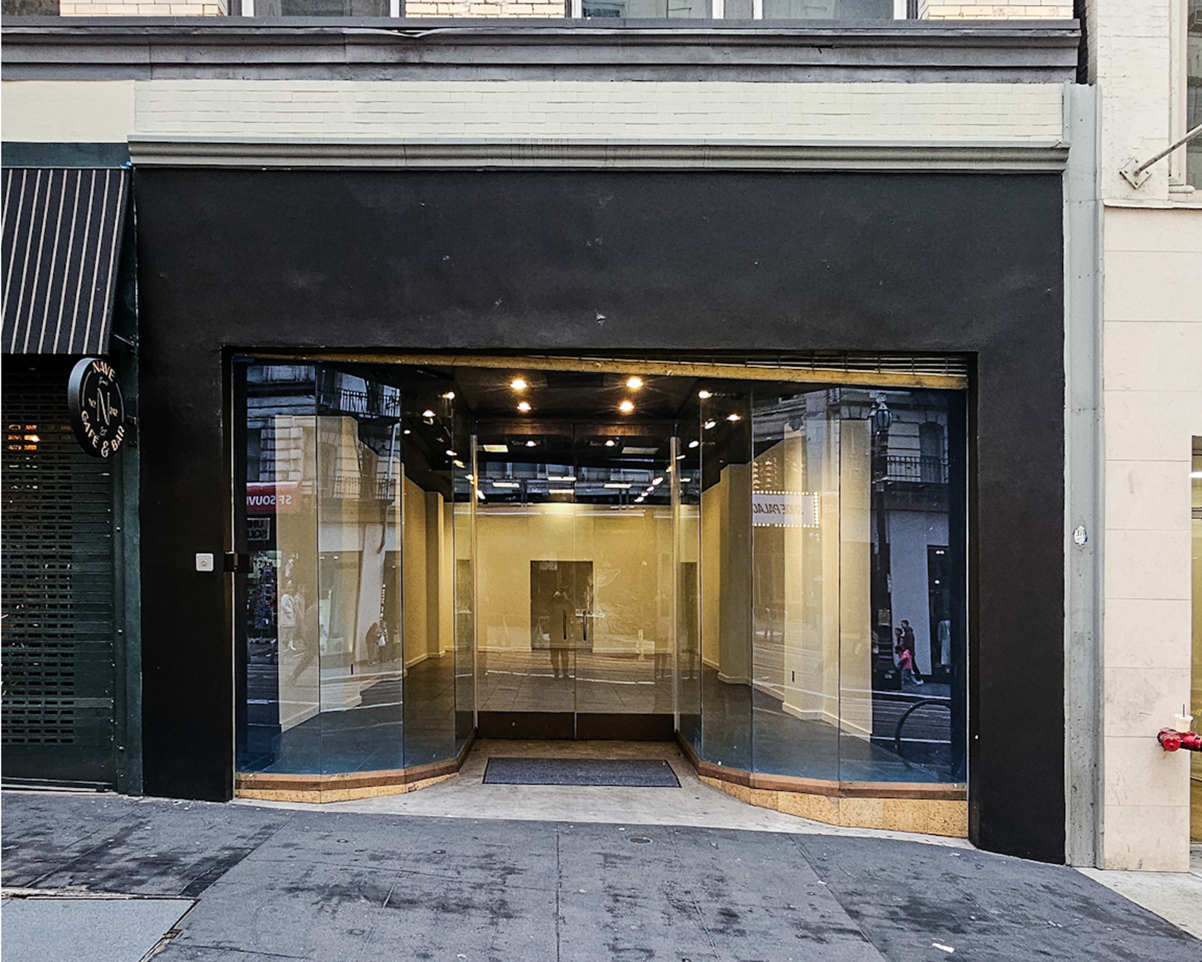 The image shows a modern glass storefront with a black exterior located on a city street.