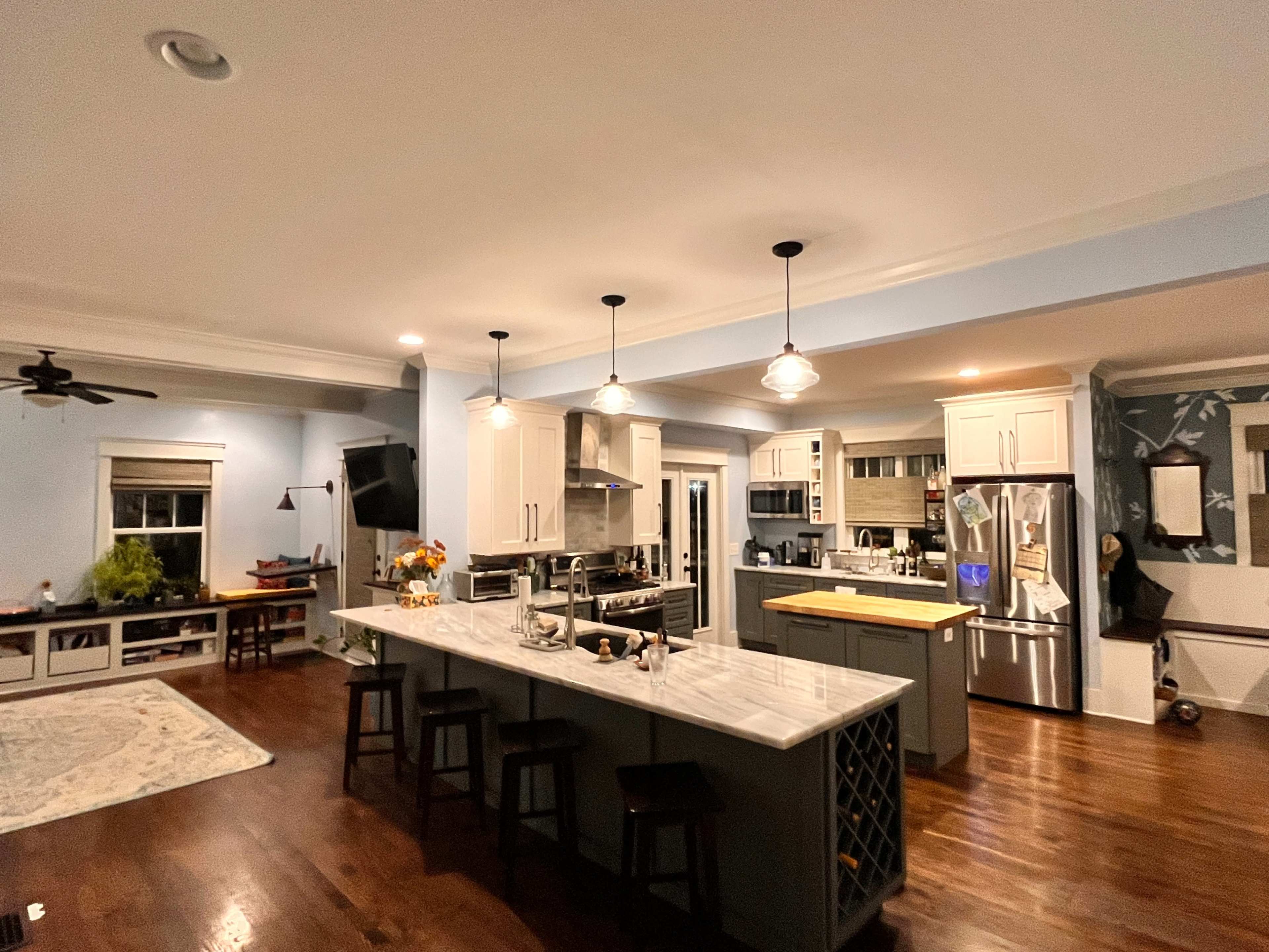 A modern kitchen with a large island, stainless steel appliances, and wooden flooring.