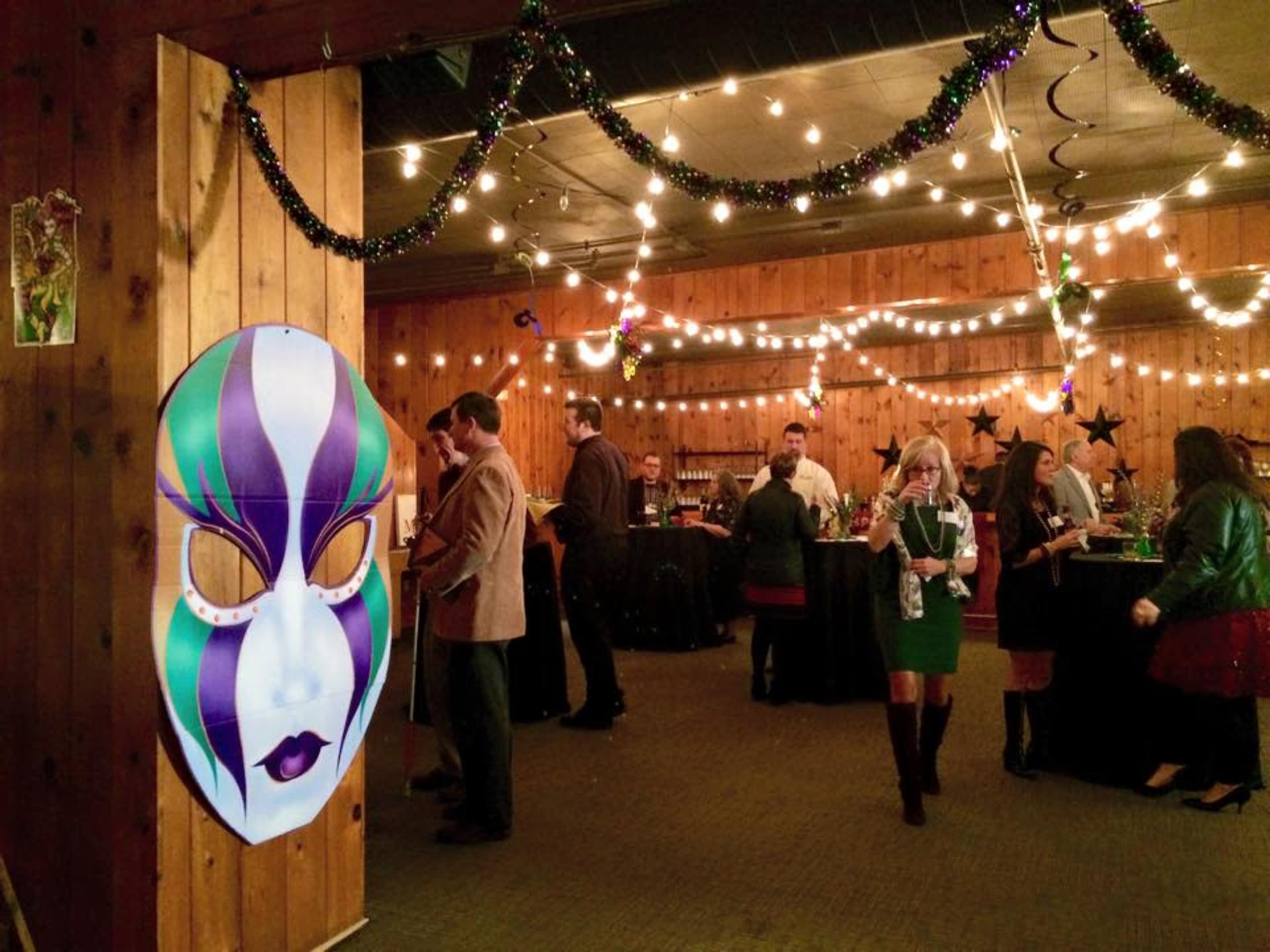 A festive party scene features guests mingling in a decorated room with string lights and a large decorative mask on the wall.