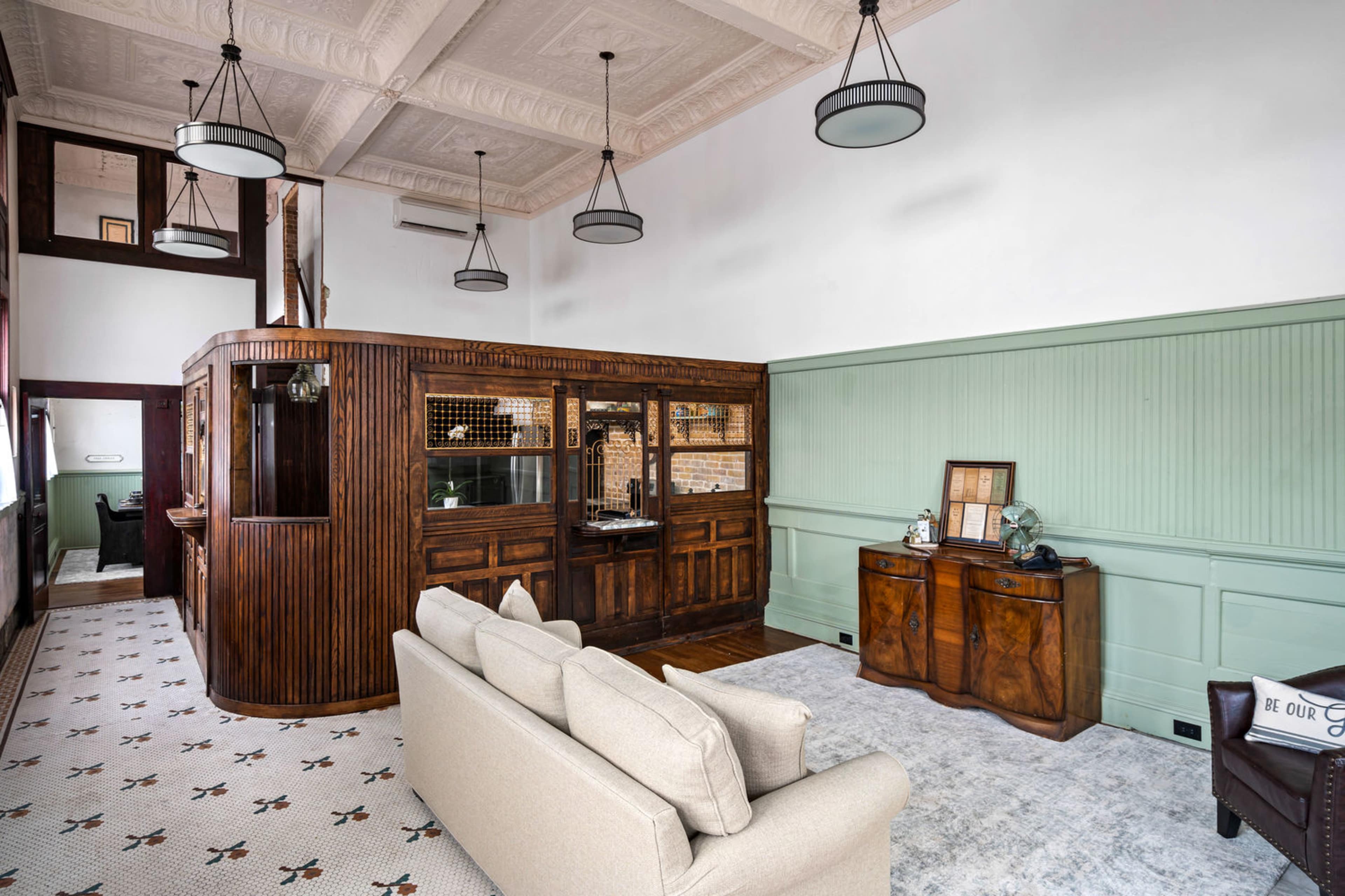 A spacious room featuring wooden paneling, a decorative curved counter, and a seating area with a beige sofa.