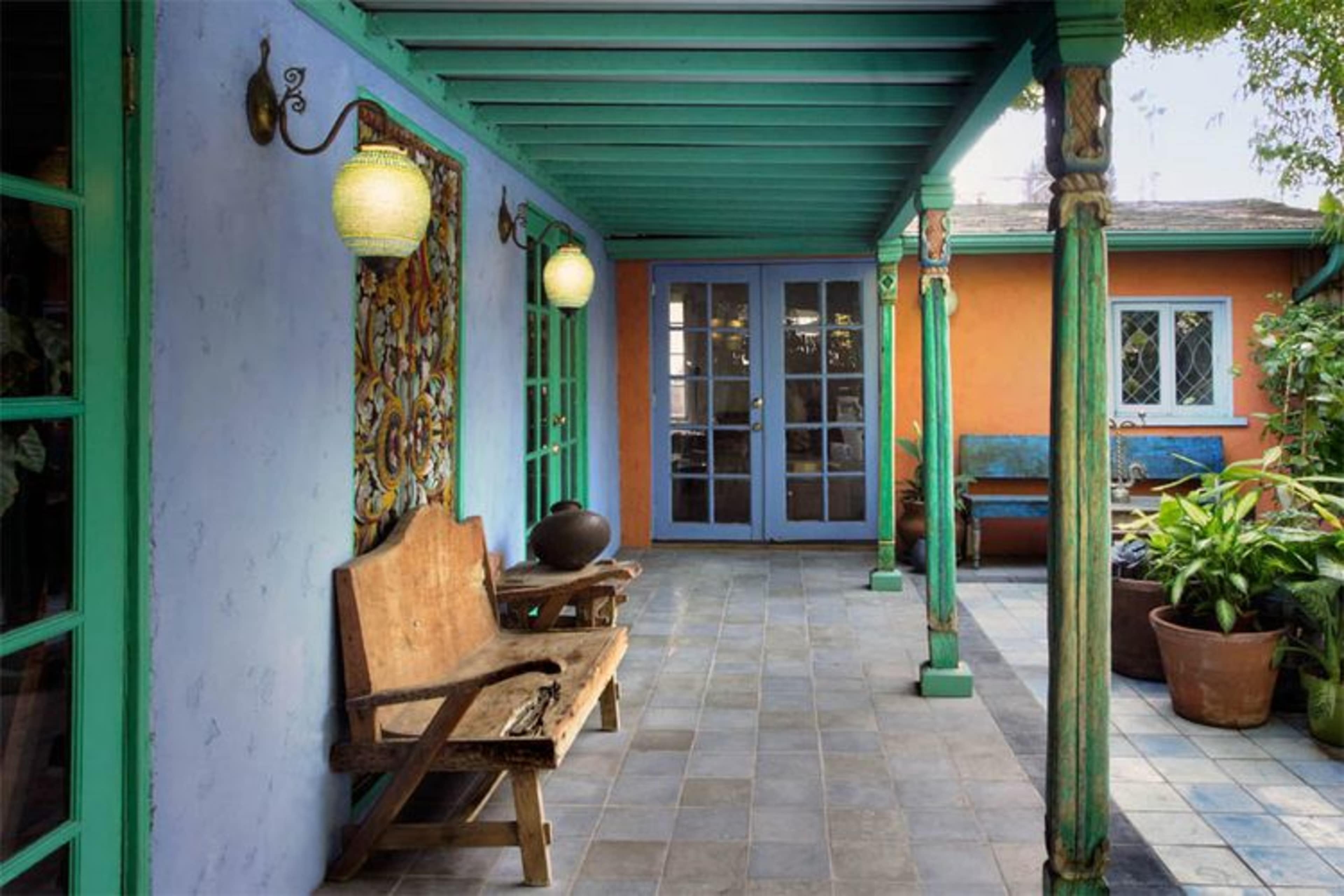 A porch area features a tiled floor, wooden benches, and colorful walls with lanterns hanging from the ceiling.