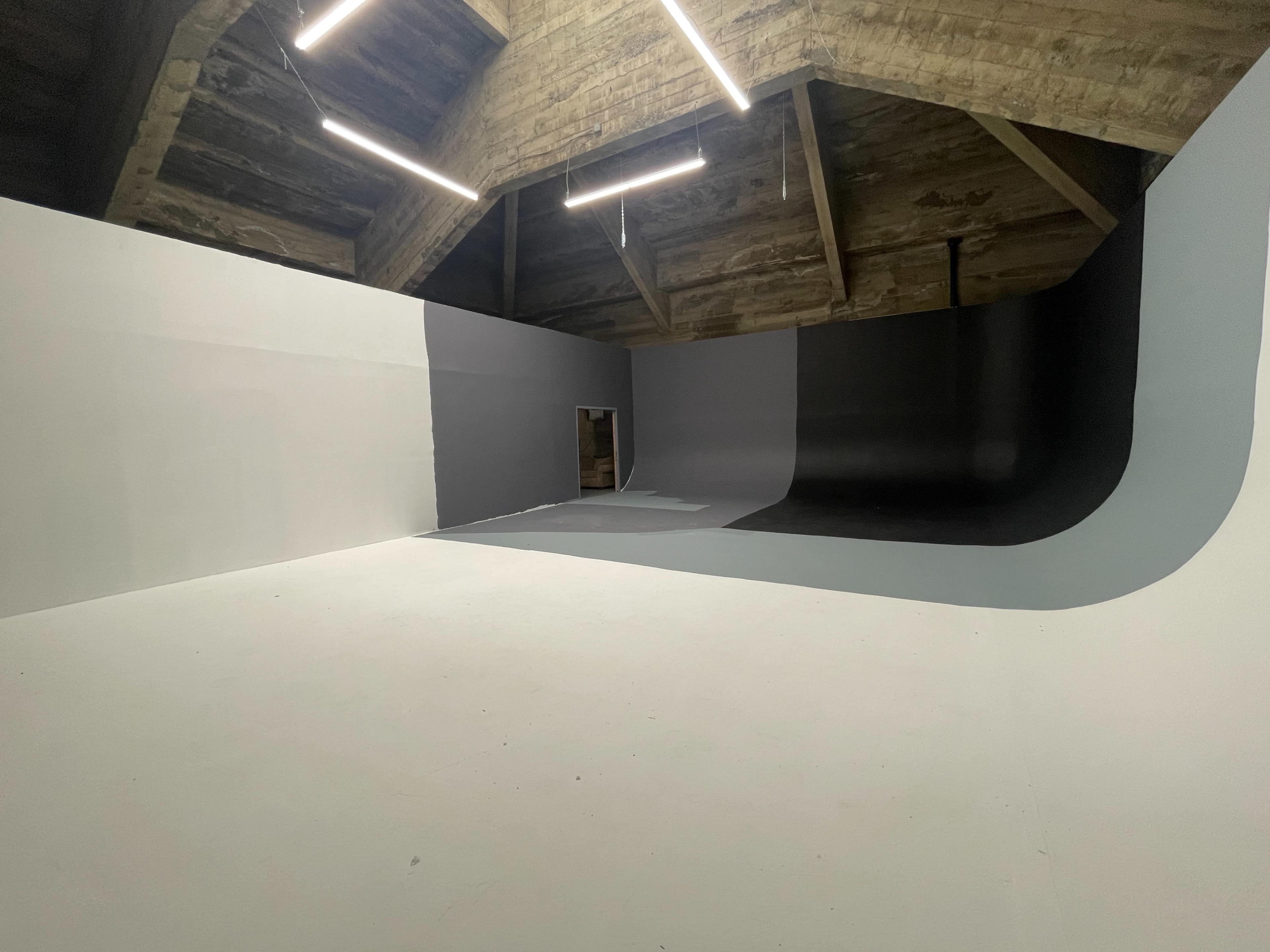 A spacious room with a curved wall design that features three different shades of gray and a door at one end.