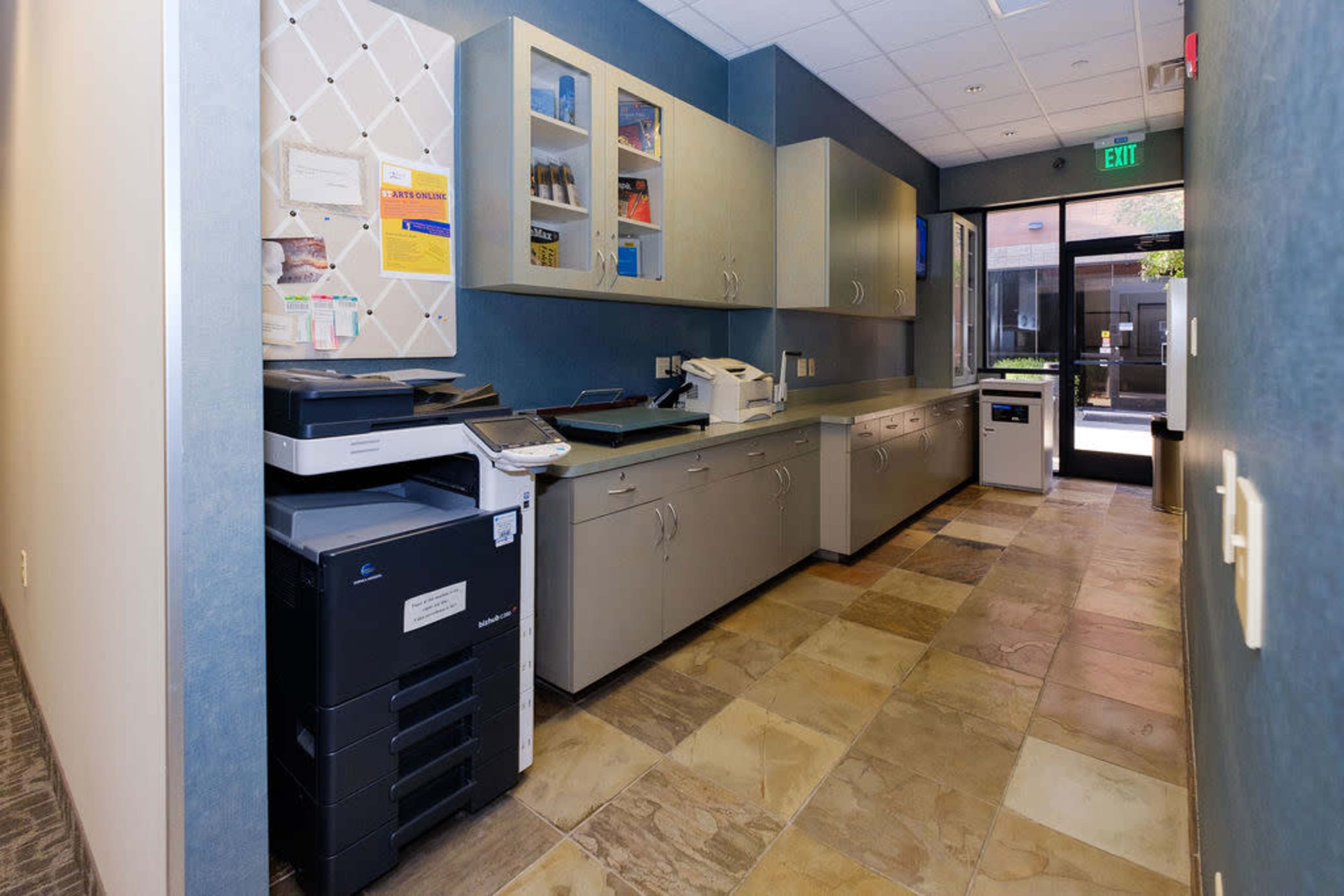 A corridor featuring a photocopy machine, cabinets, and a door leading to an outdoor area.