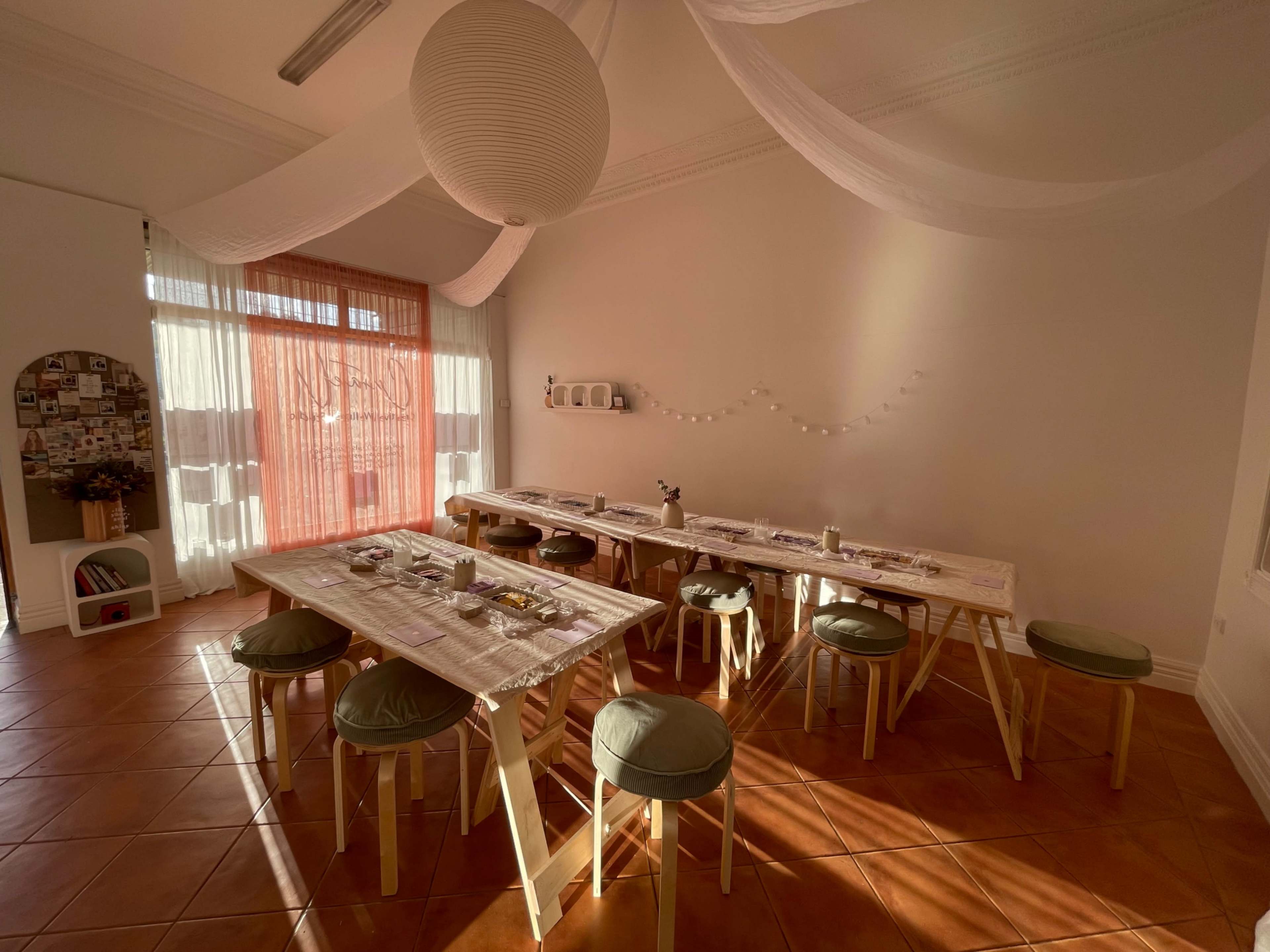 A spacious dining area features several tables set with plates and cutlery, illuminated by natural light from large windows.