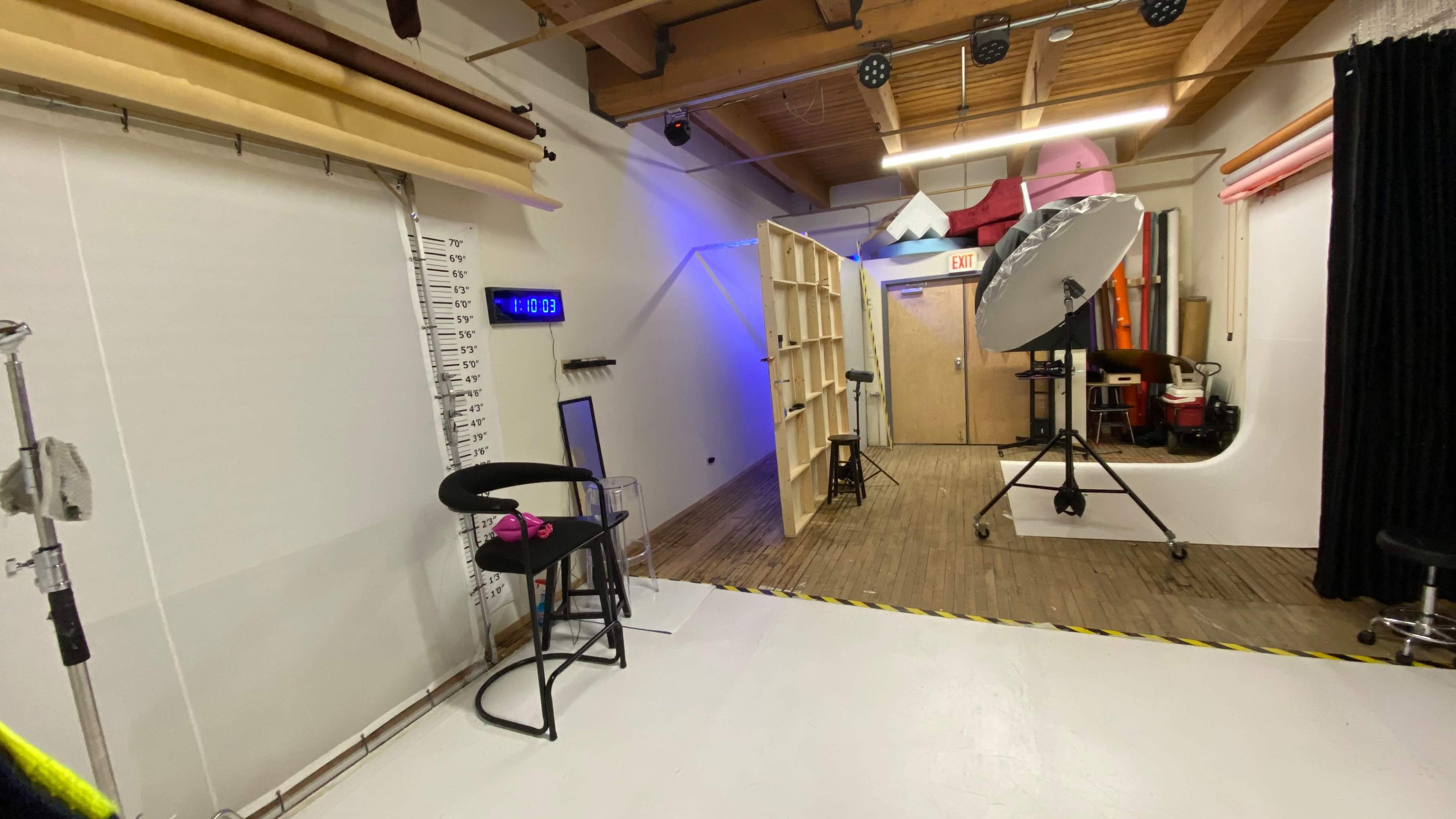A photography studio with various backdrops, lighting equipment, and props arranged around a white floor.