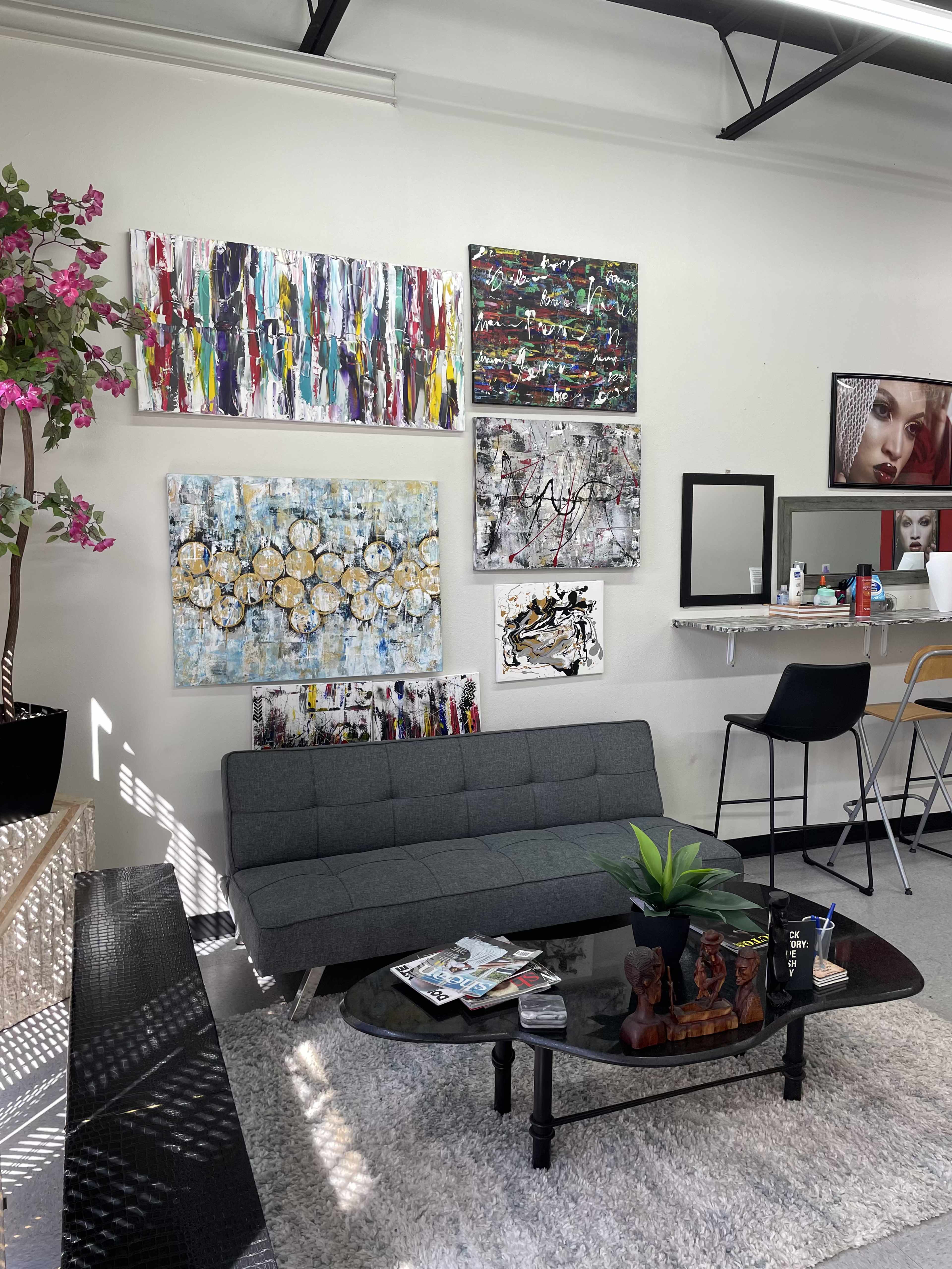 A modern interior features a gray sofa and a coffee table adorned with decorative items, surrounded by colorful abstract artwork on the walls.