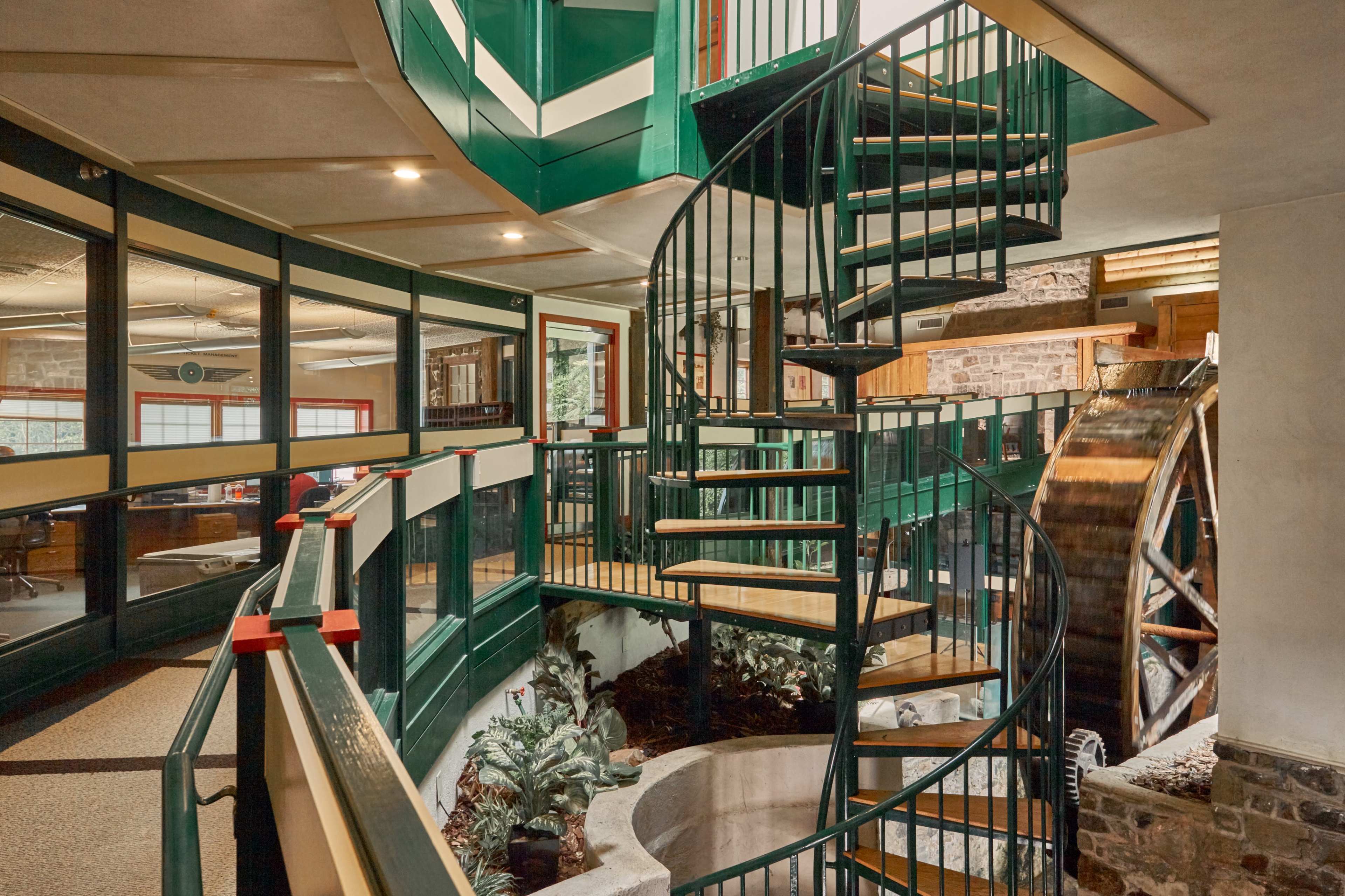 A modern interior with a spiral staircase, surrounded by glass walls and wooden features, leading to multiple levels.