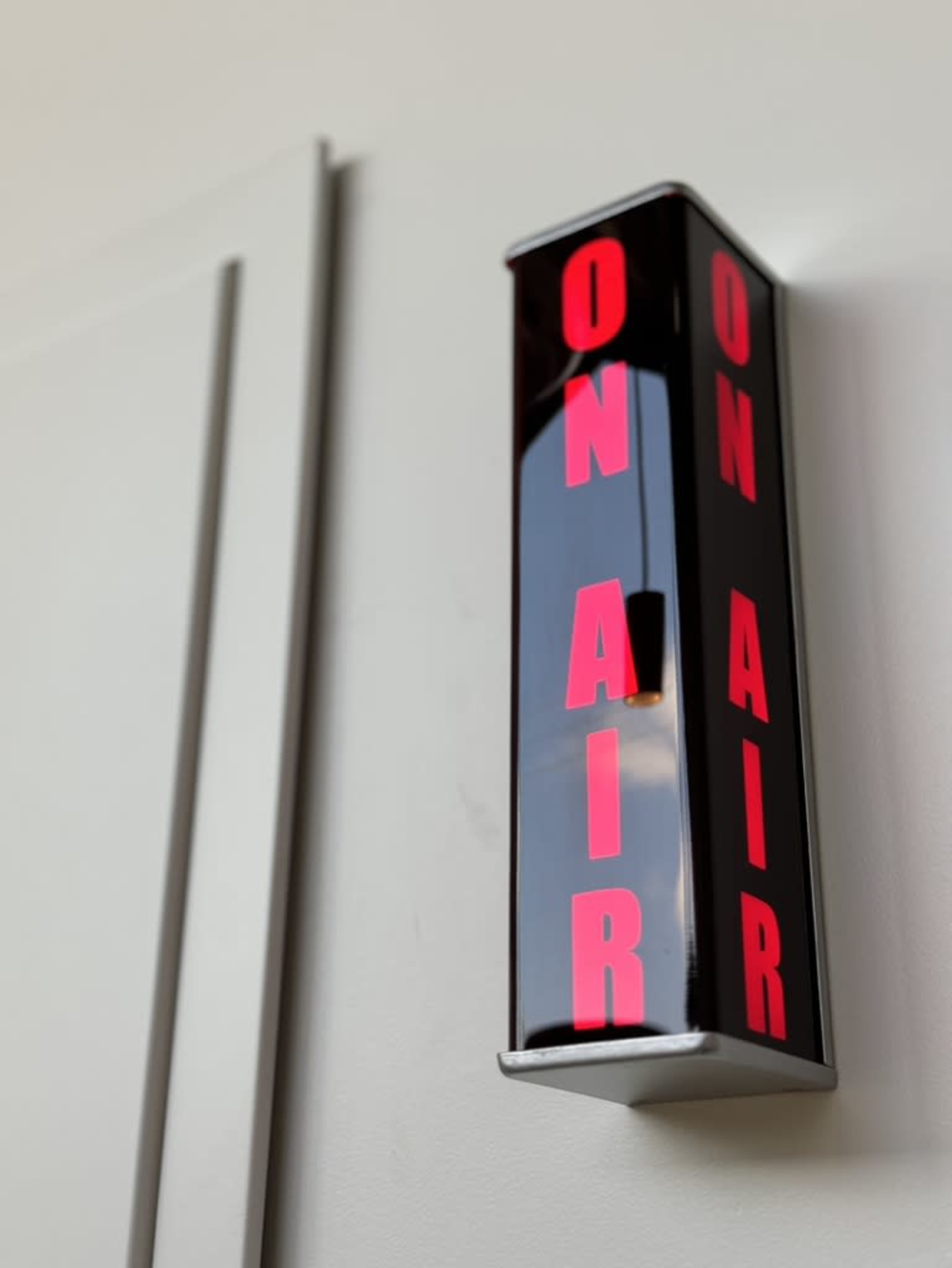A black "ON AIR" sign with red letters is mounted on a wall.