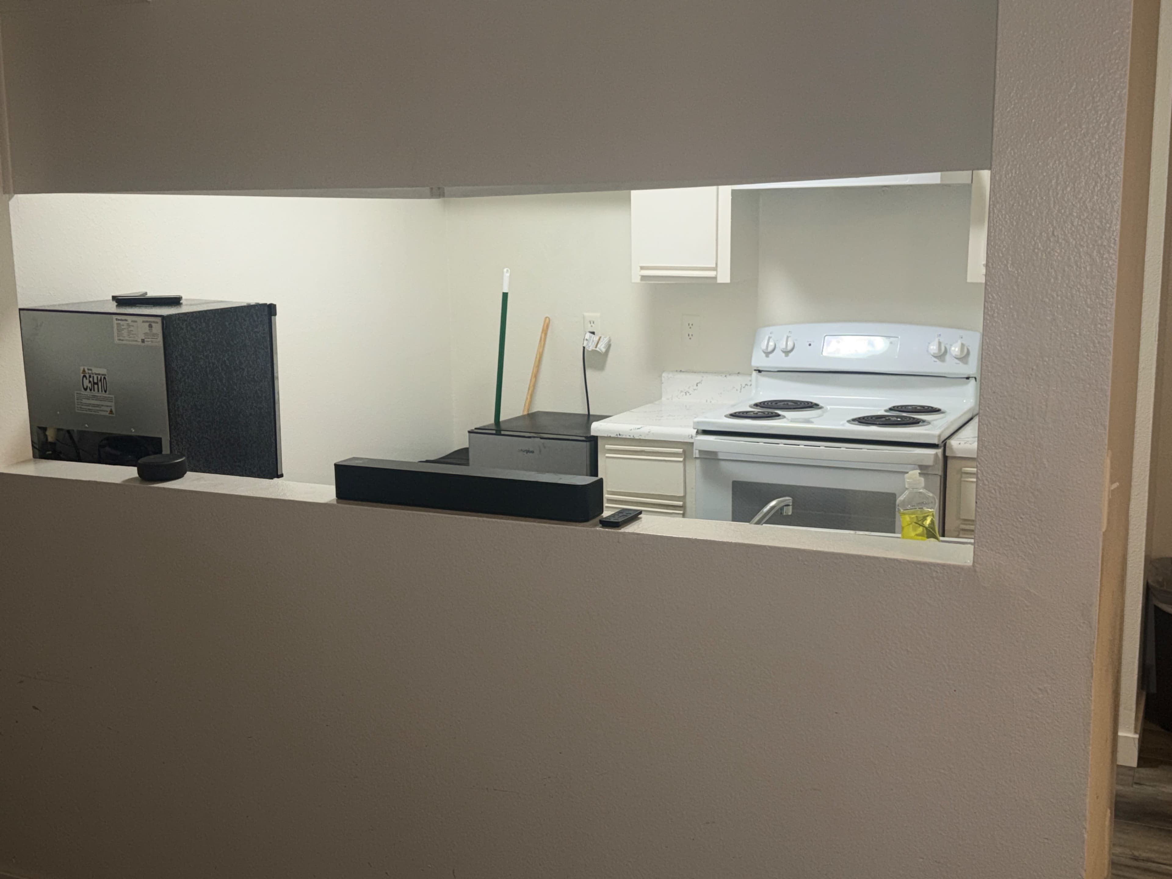 The image shows a view of a kitchen with a gray stove, counter, and a monitor set up on the left side of an open wall.