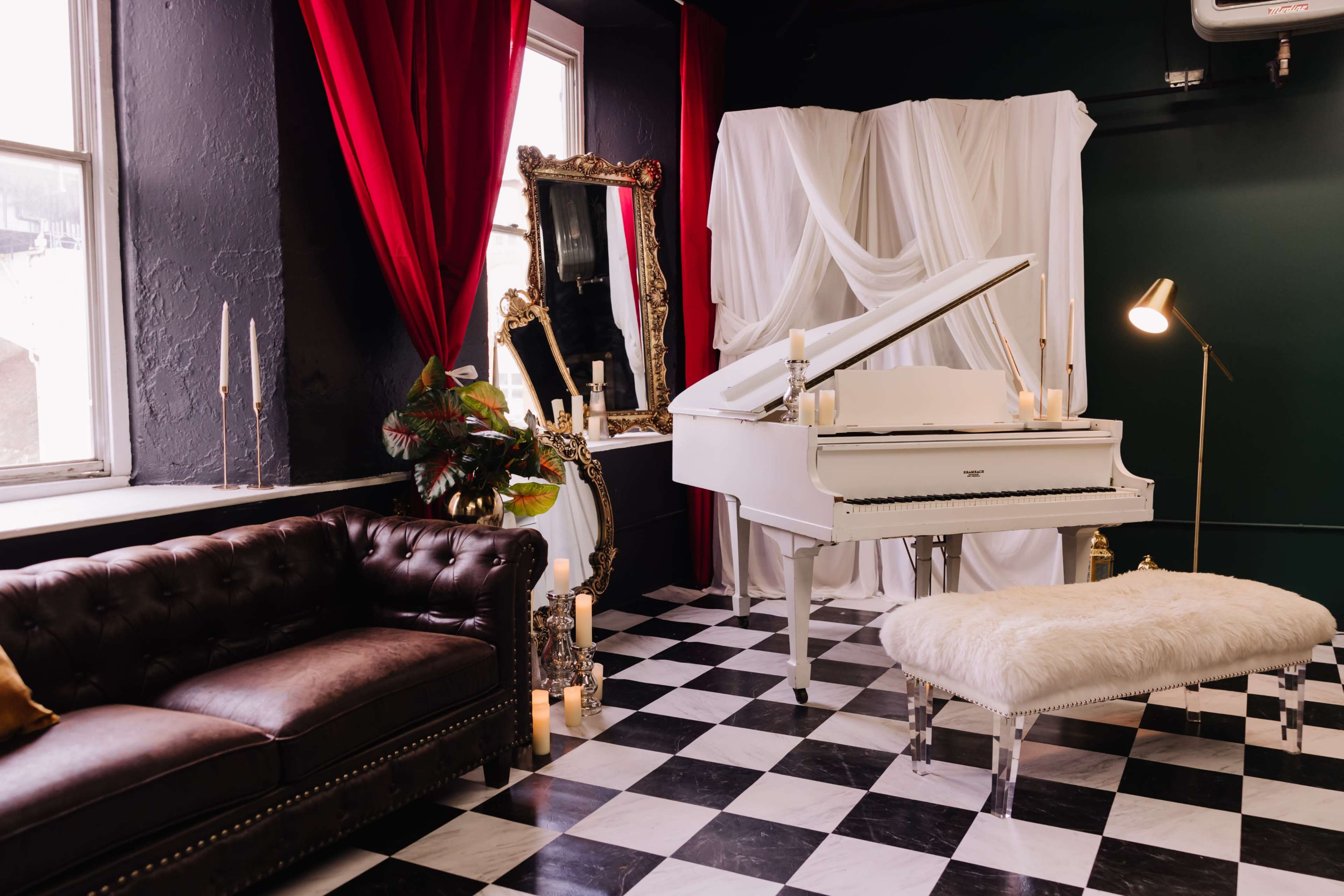 The scene features a white grand piano in a room adorned with red curtains, a large mirror, and a black-and-white checkered floor, accompanied by a dark sofa and a plush bench.