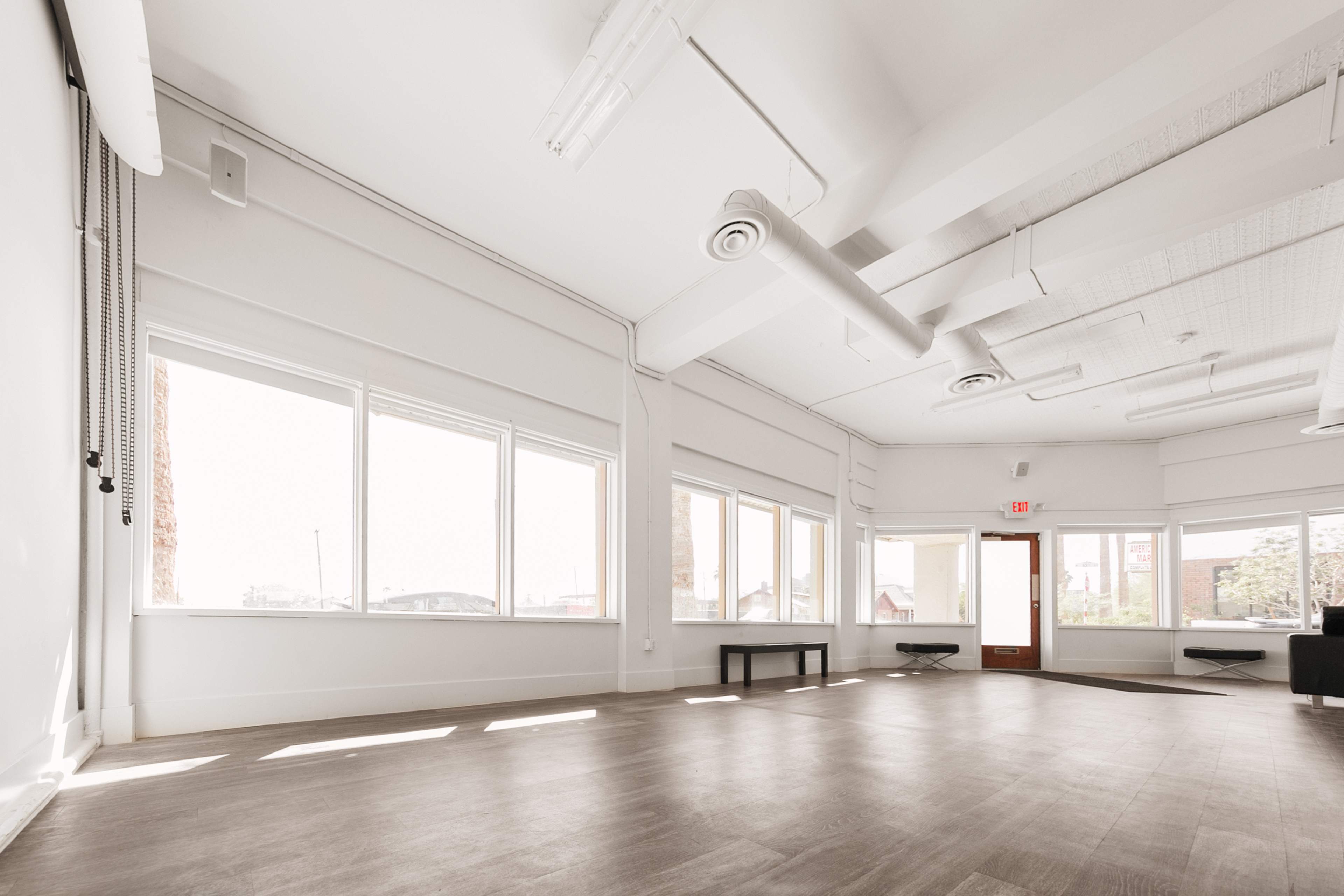 A bright, empty room with large windows and a wooden floor.