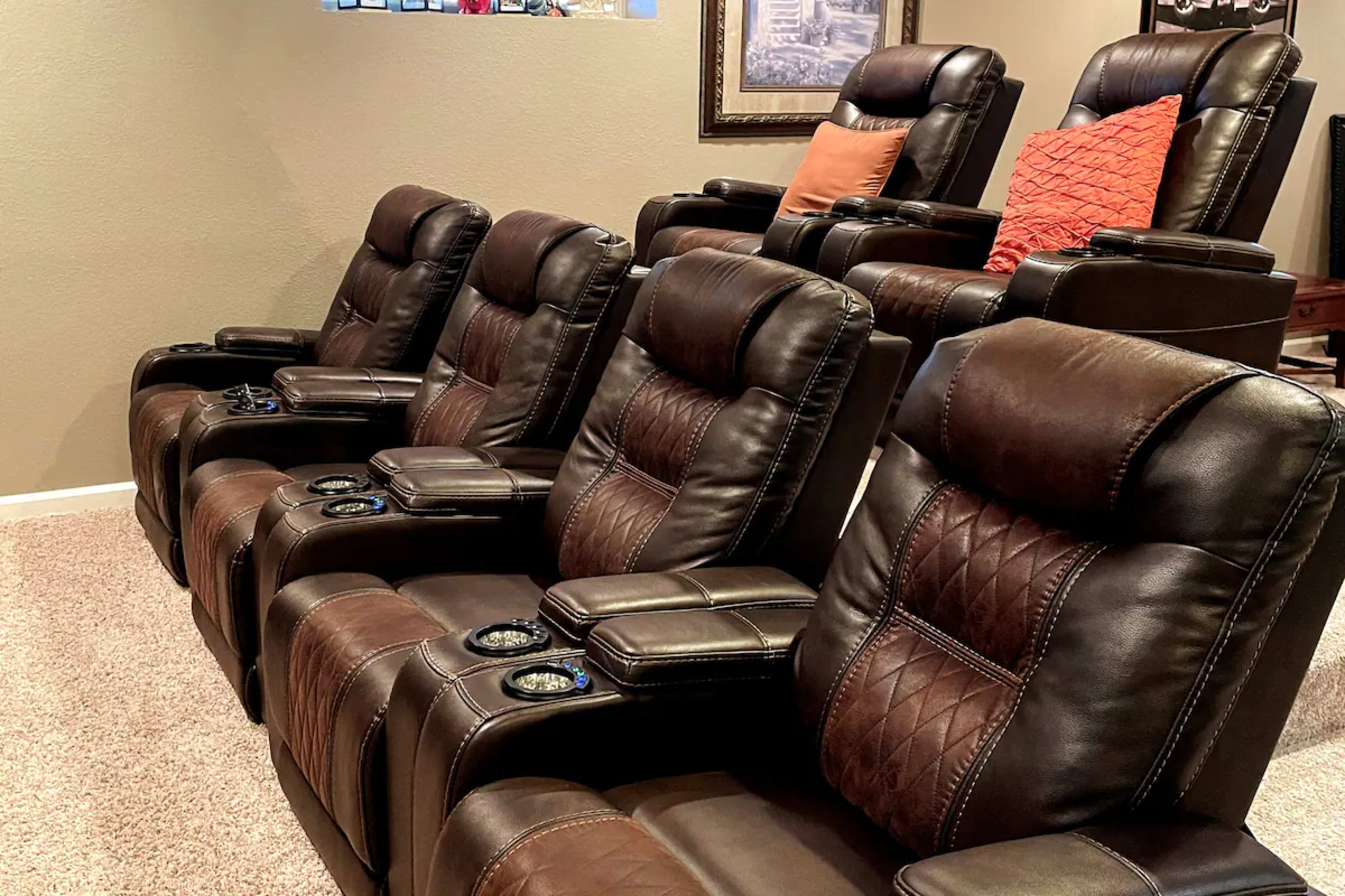 A row of five brown leather recliner chairs arranged in a home theater setting.