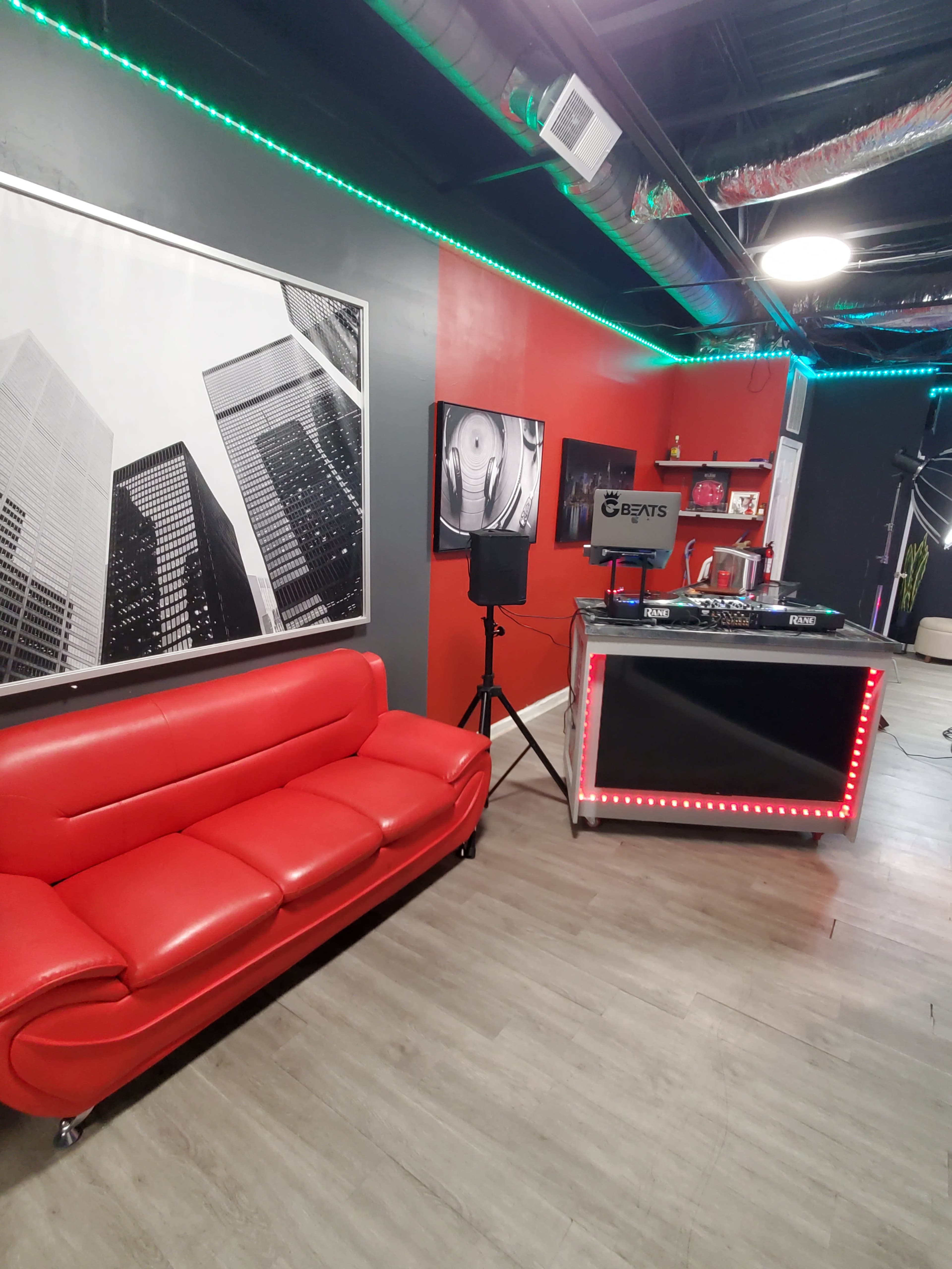The image shows a modern interior with a red sofa, a display area featuring a black table with lights, and wall art of skyscrapers.
