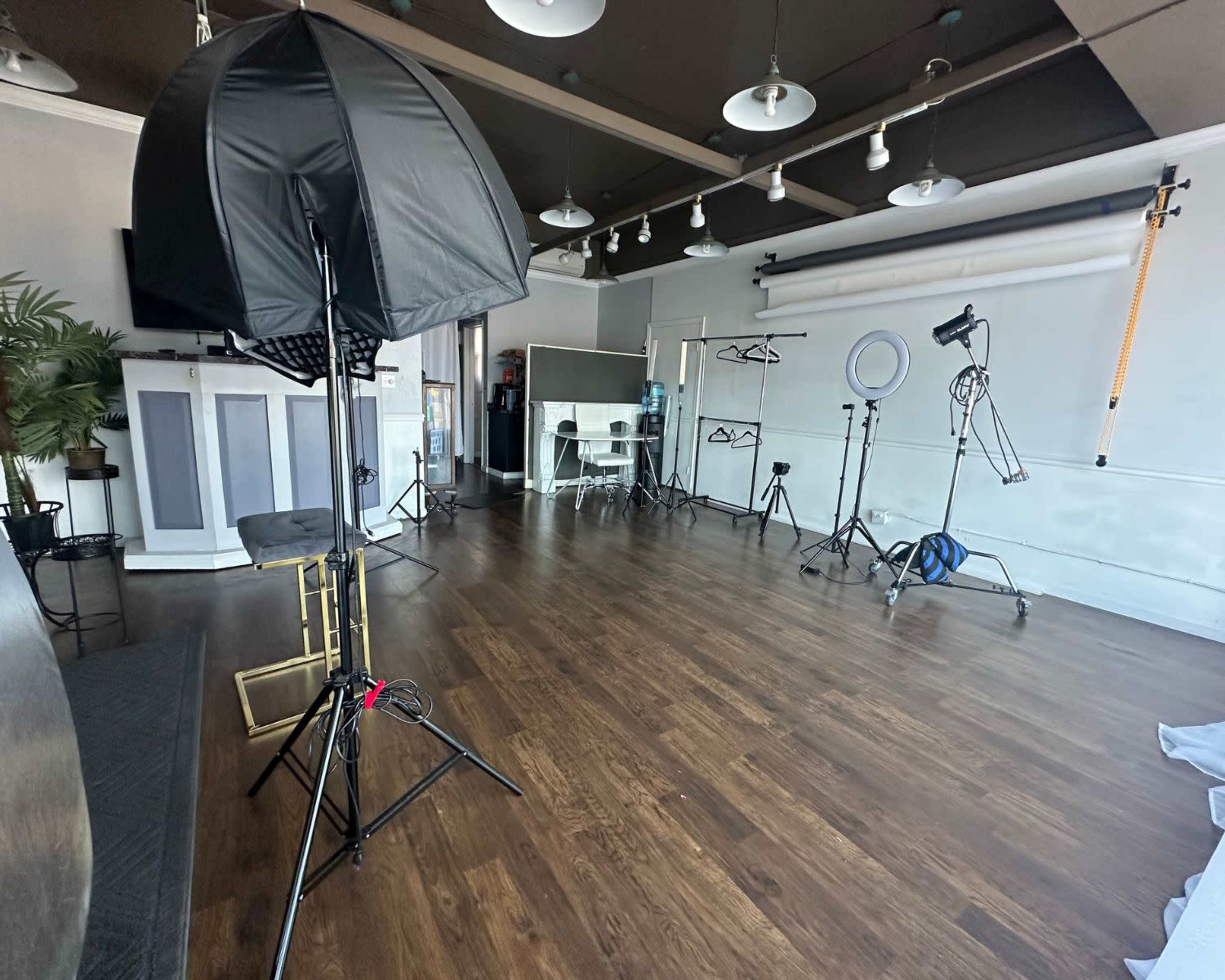 A photography studio with lighting equipment, backdrops, and props set up on a wooden floor.