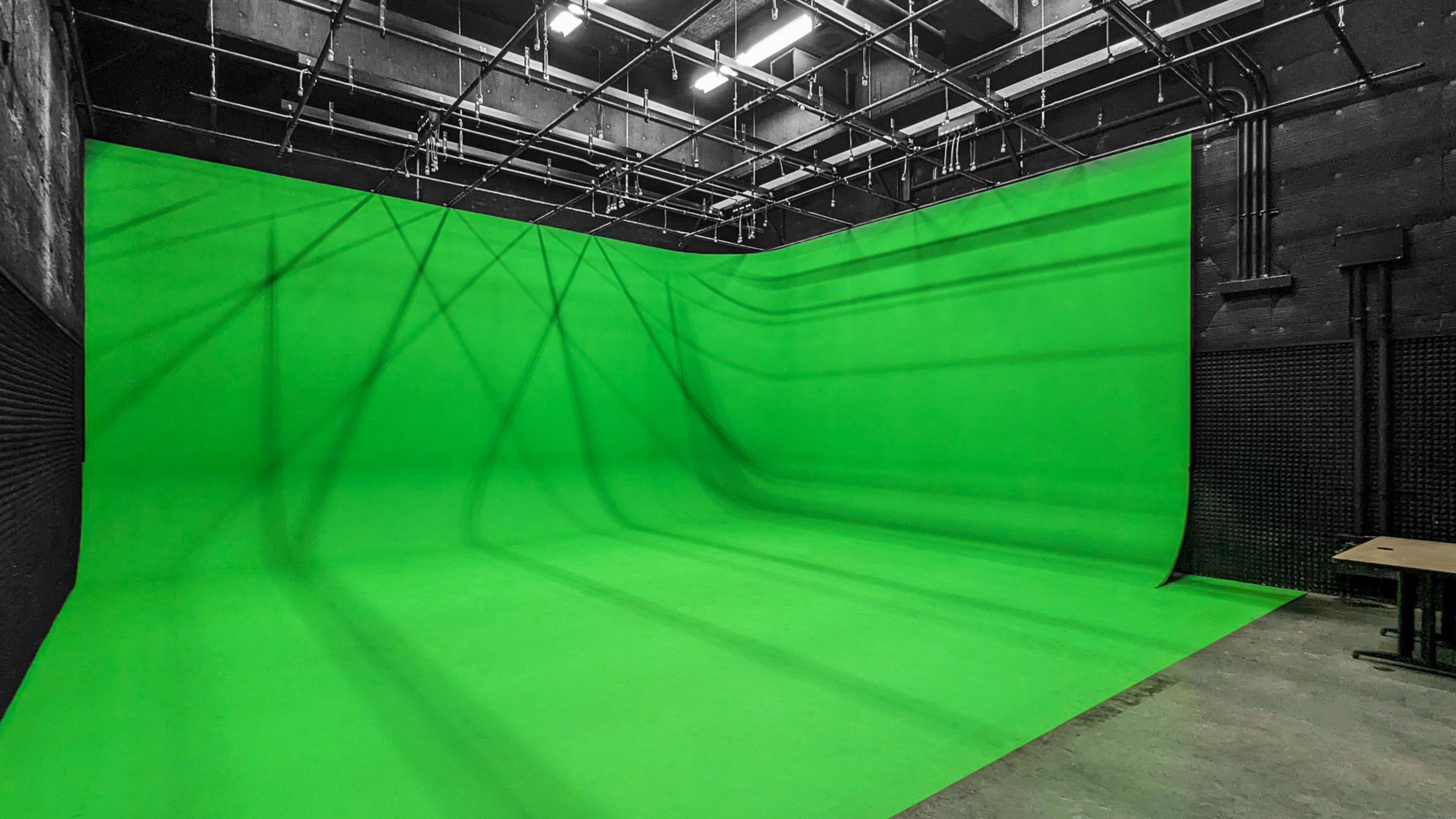 The image shows a large, green cyclorama background set in a spacious studio environment.