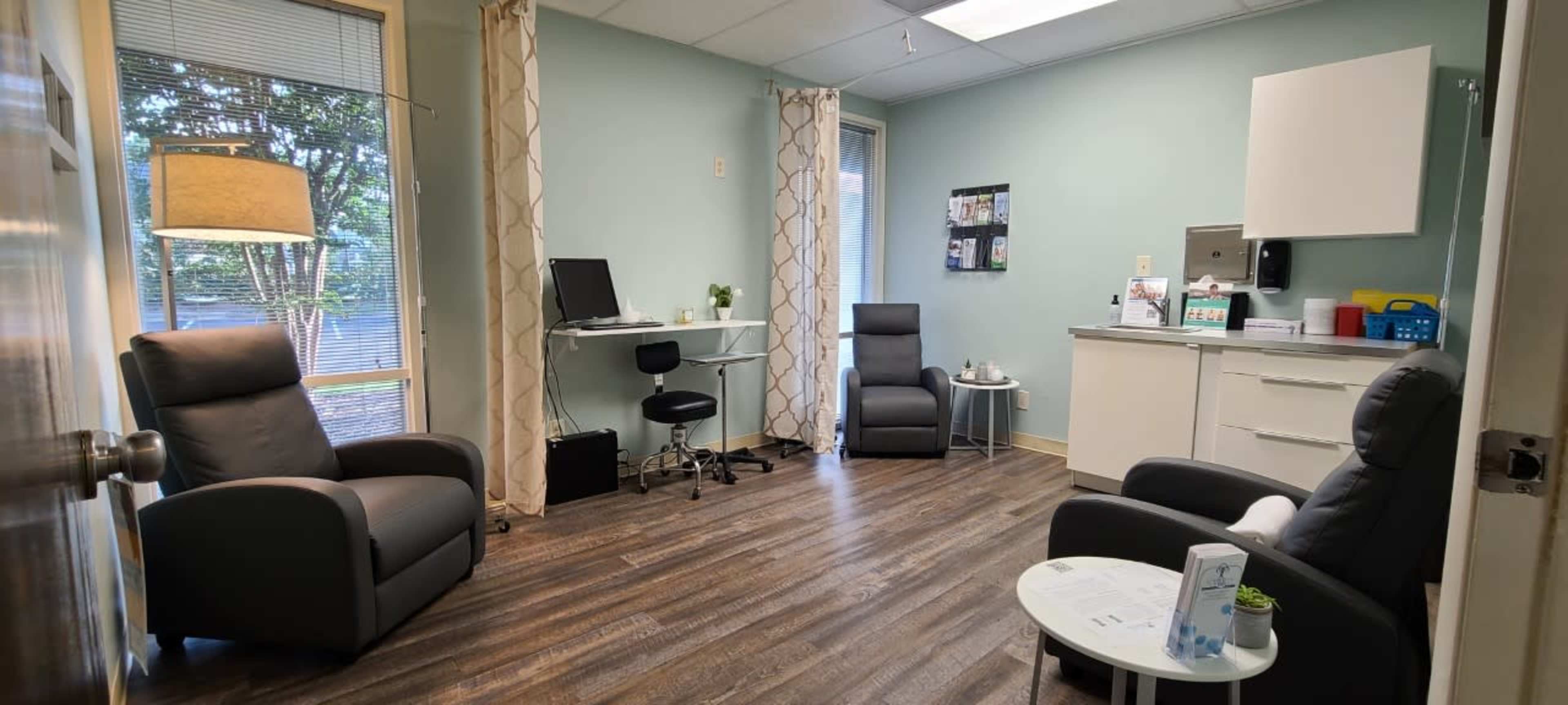 The image shows a small, well-lit office space with two chairs, a desk with a chair, and a cabinet against the wall.