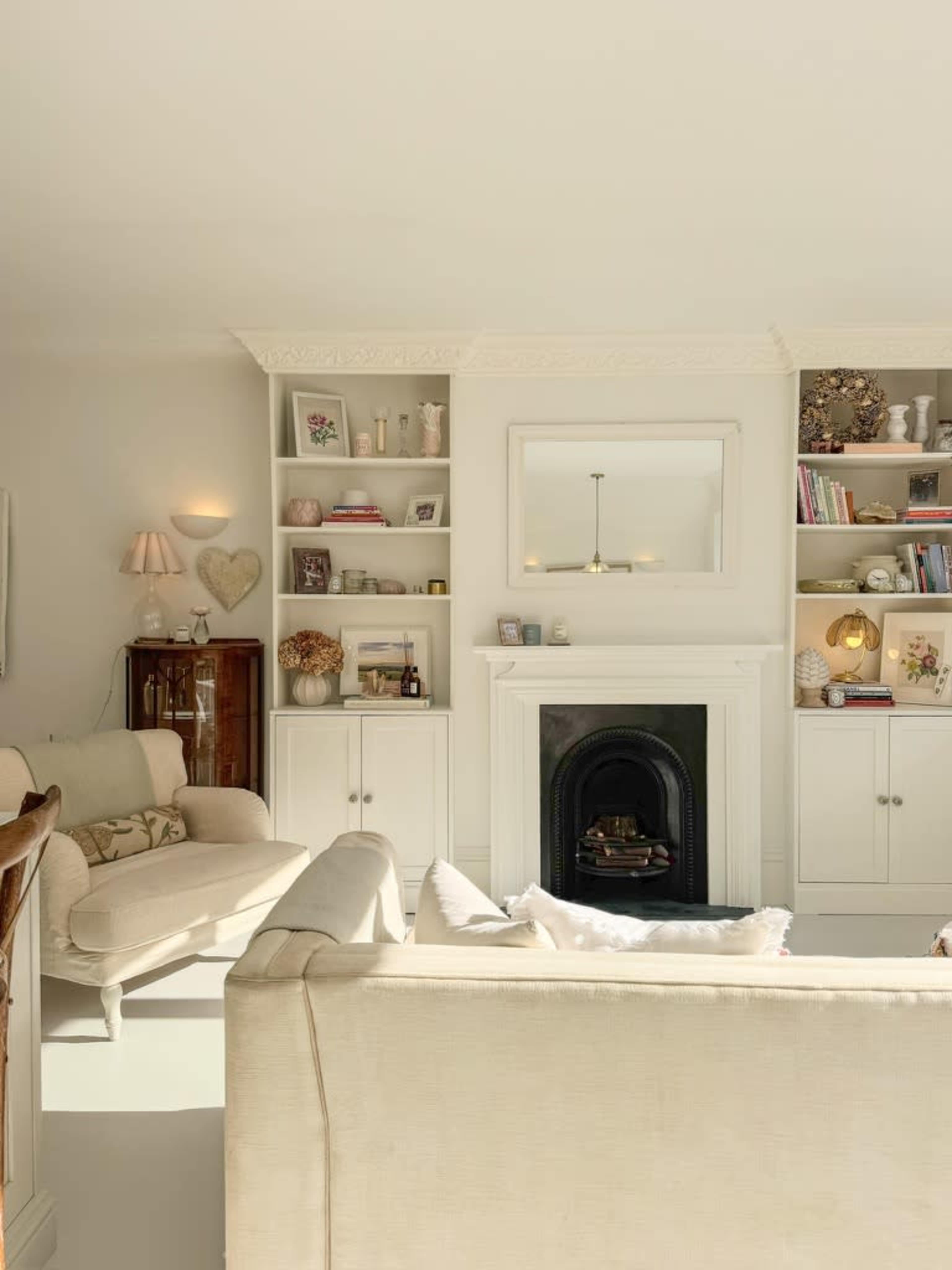 The image shows a bright living room with a fireplace and built-in shelves filled with decorative items and books.
