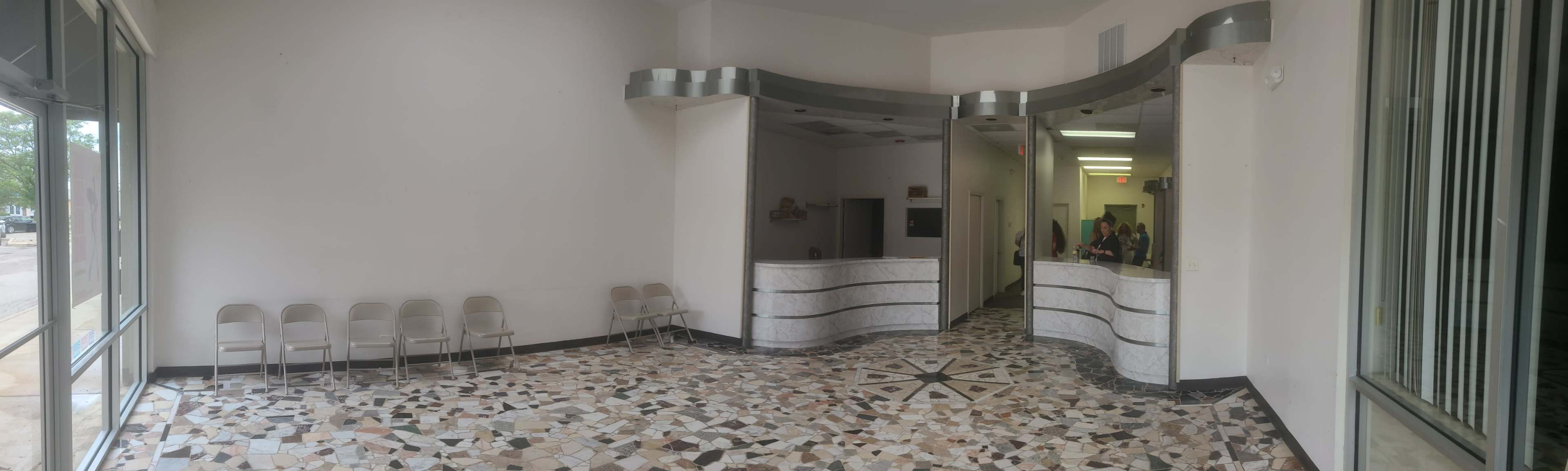 A reception area with a tiled floor, a front desk, and several chairs lined up against the wall.