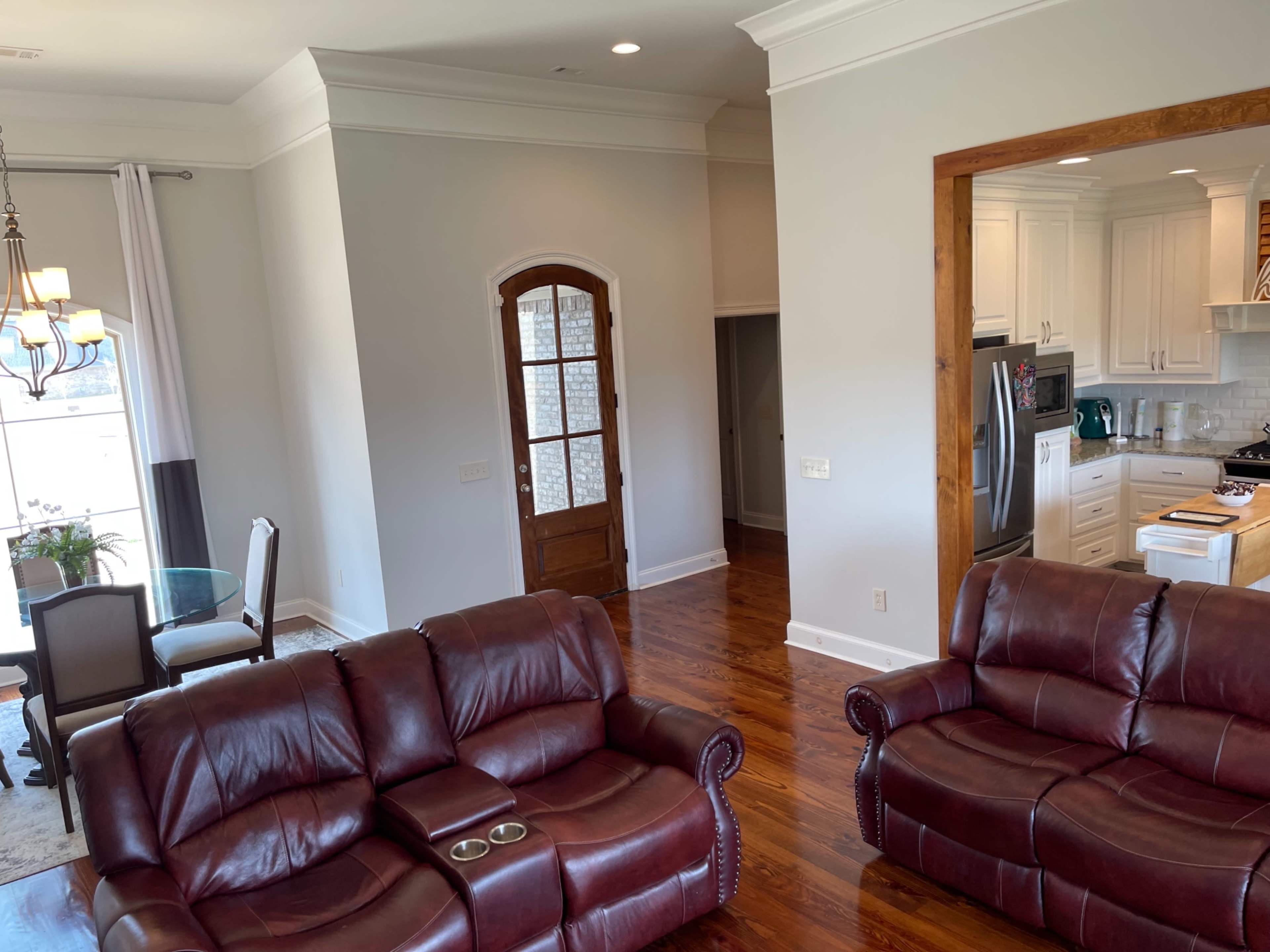 A modern living room with two brown leather sofas facing a dining area and a kitchen.