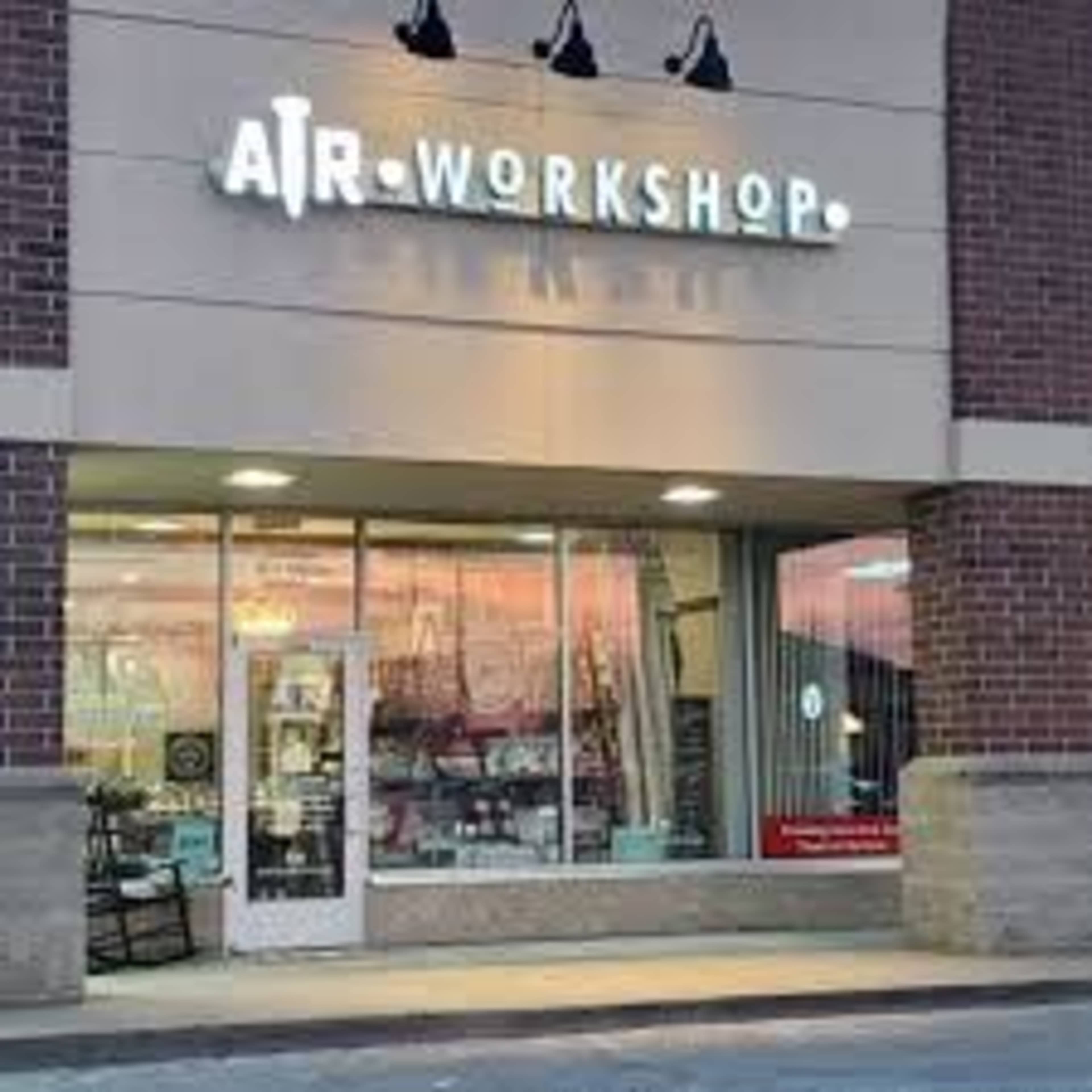 The image shows a storefront labeled "AIR WORKSHOP" with large windows displaying various items inside.