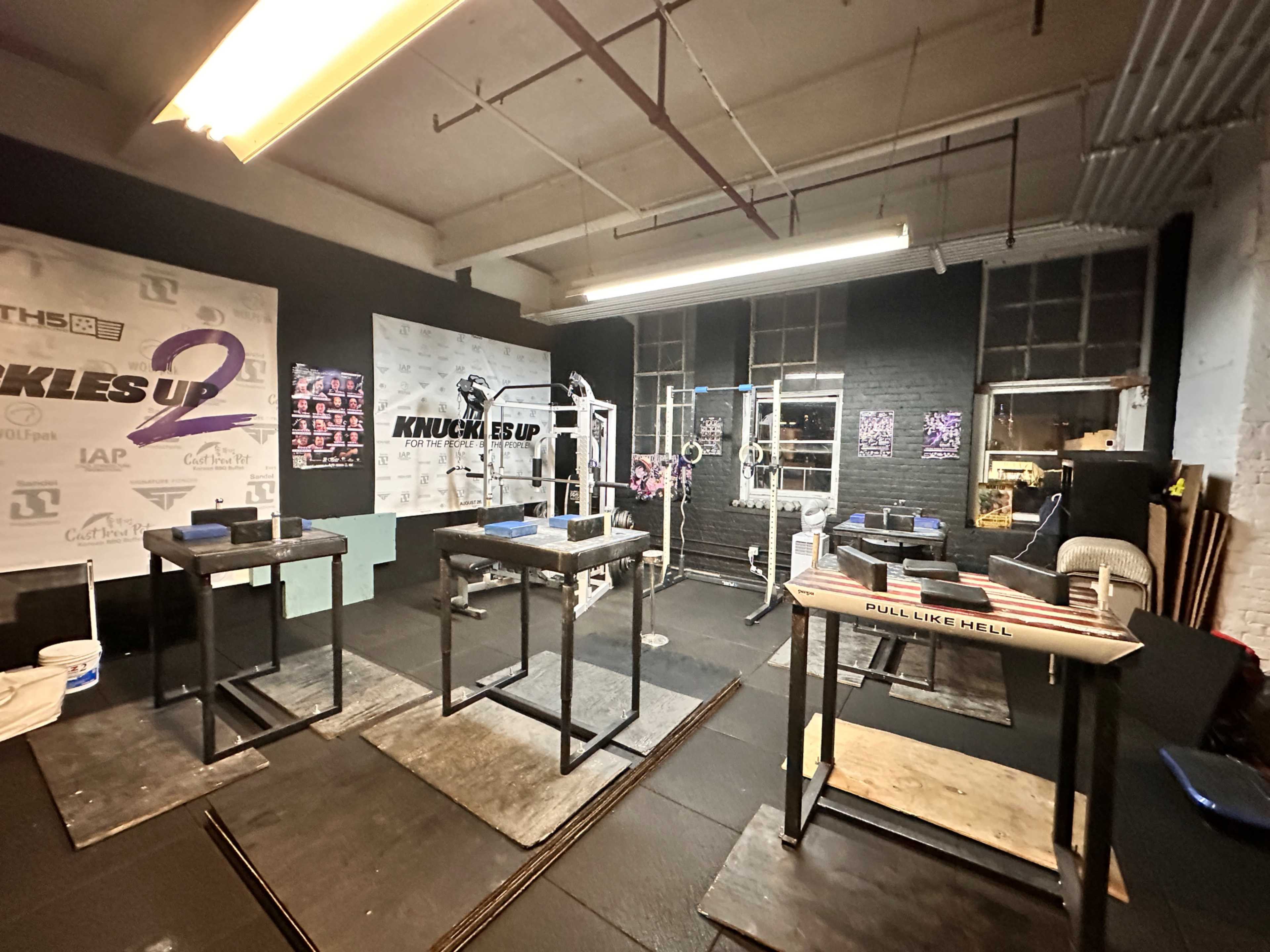 The image shows a gym space with several weightlifting benches, exercise equipment, and motivational wall art.