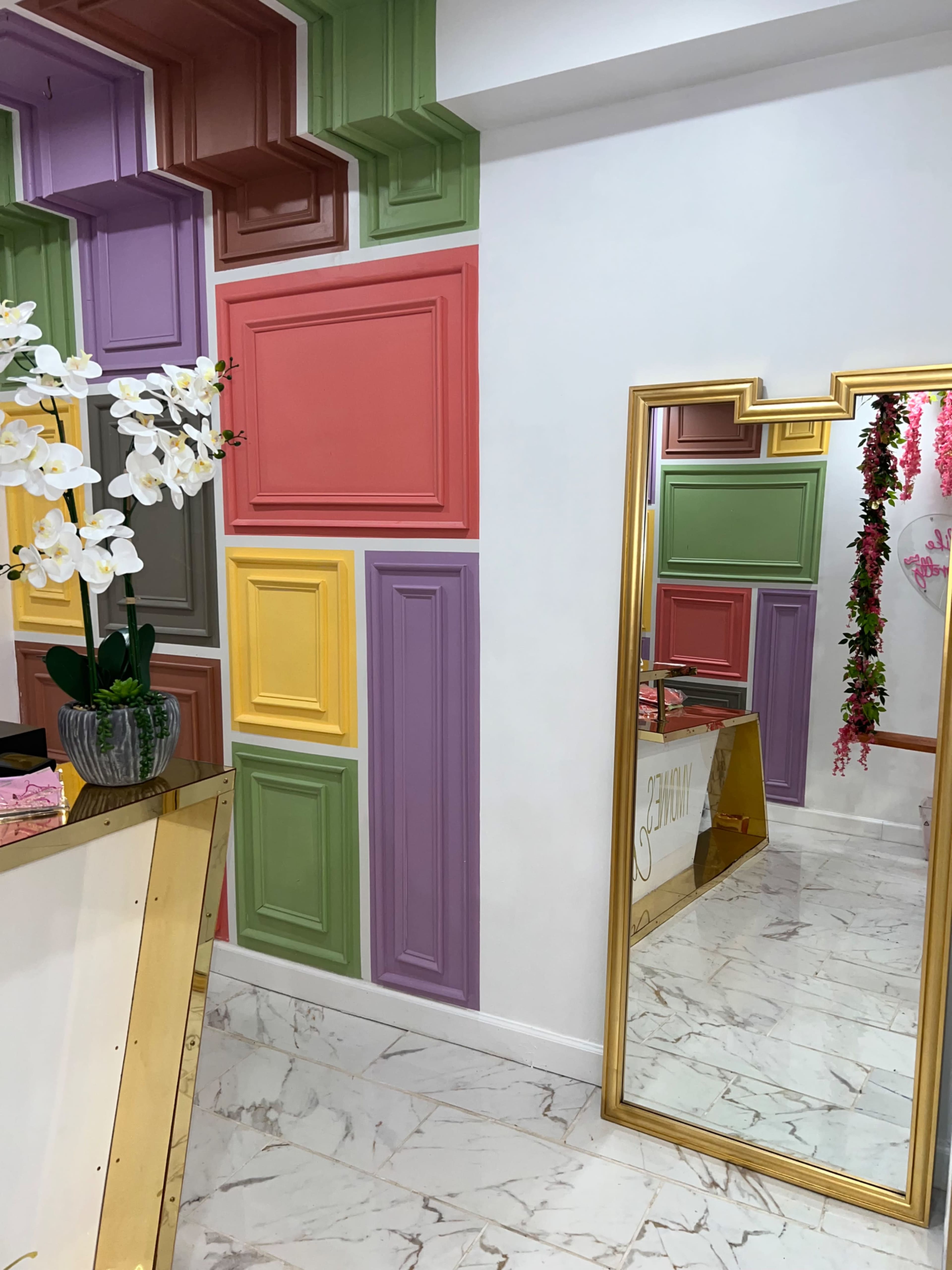 A brightly colored interior with decorative paneling on the walls and a large mirror reflecting the surroundings.