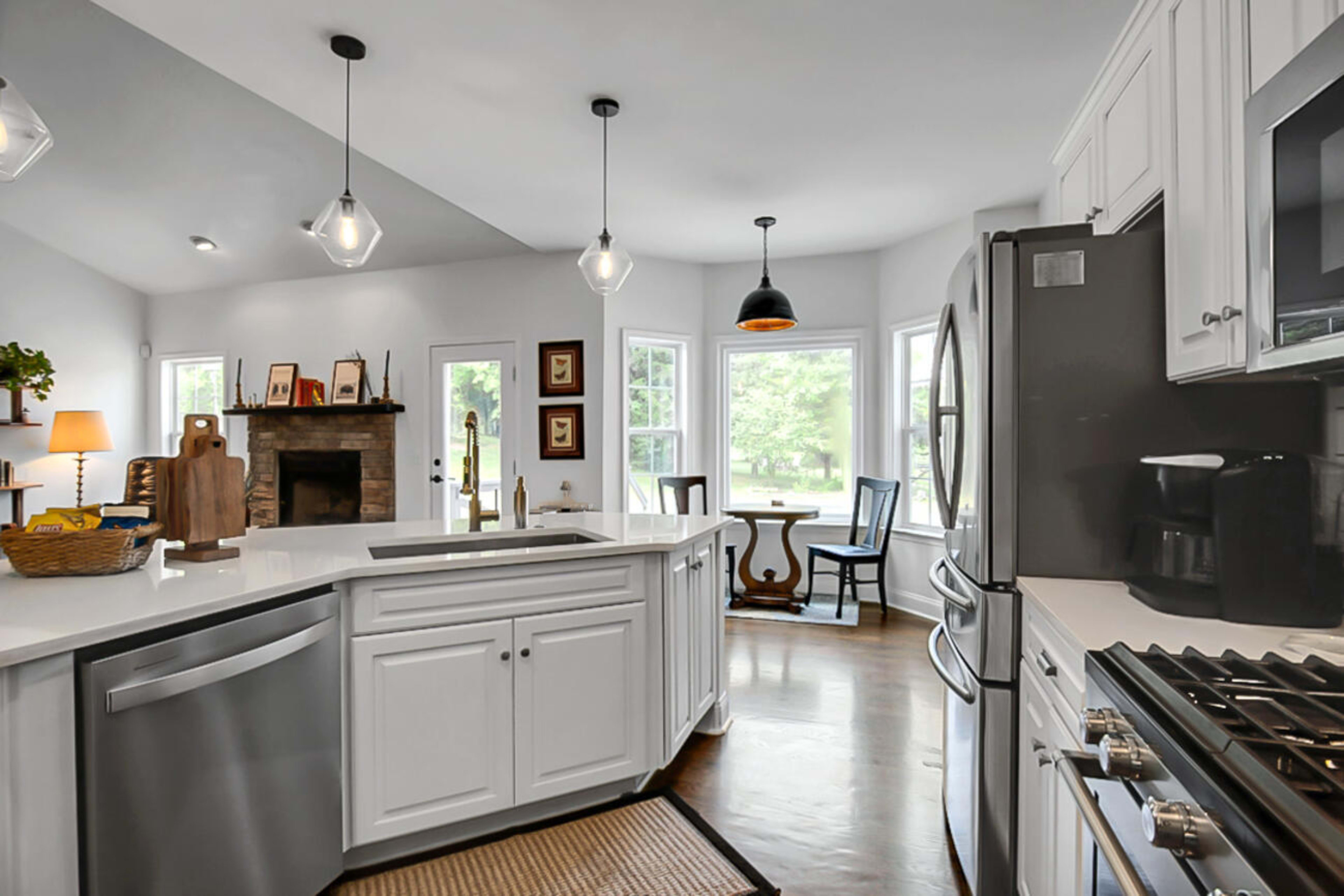 A bright kitchen features white cabinets, stainless steel appliances, and a cozy dining area with a view of the outdoors.
