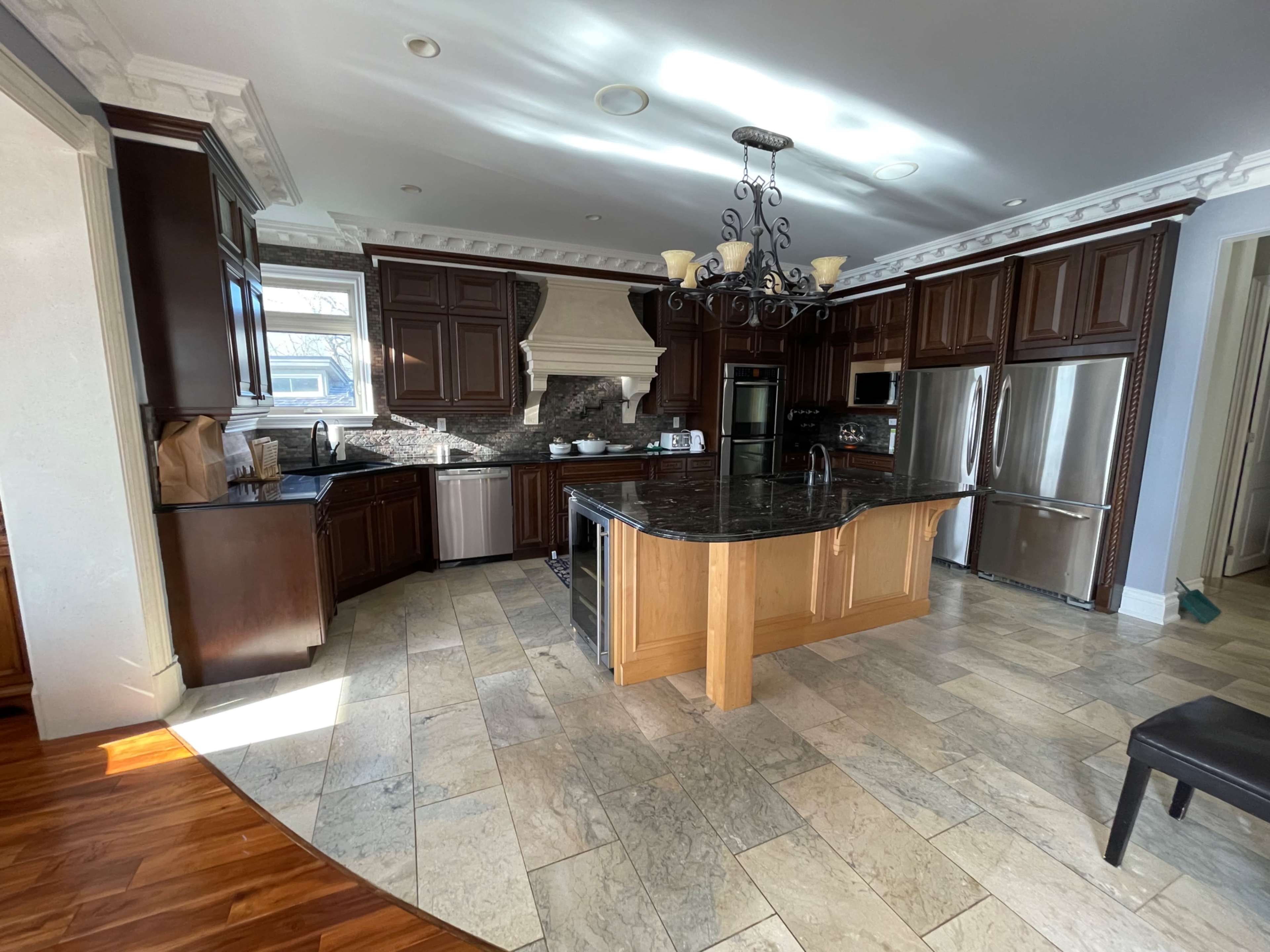 A spacious kitchen featuring dark wooden cabinets, a large granite island, and stainless steel appliances.