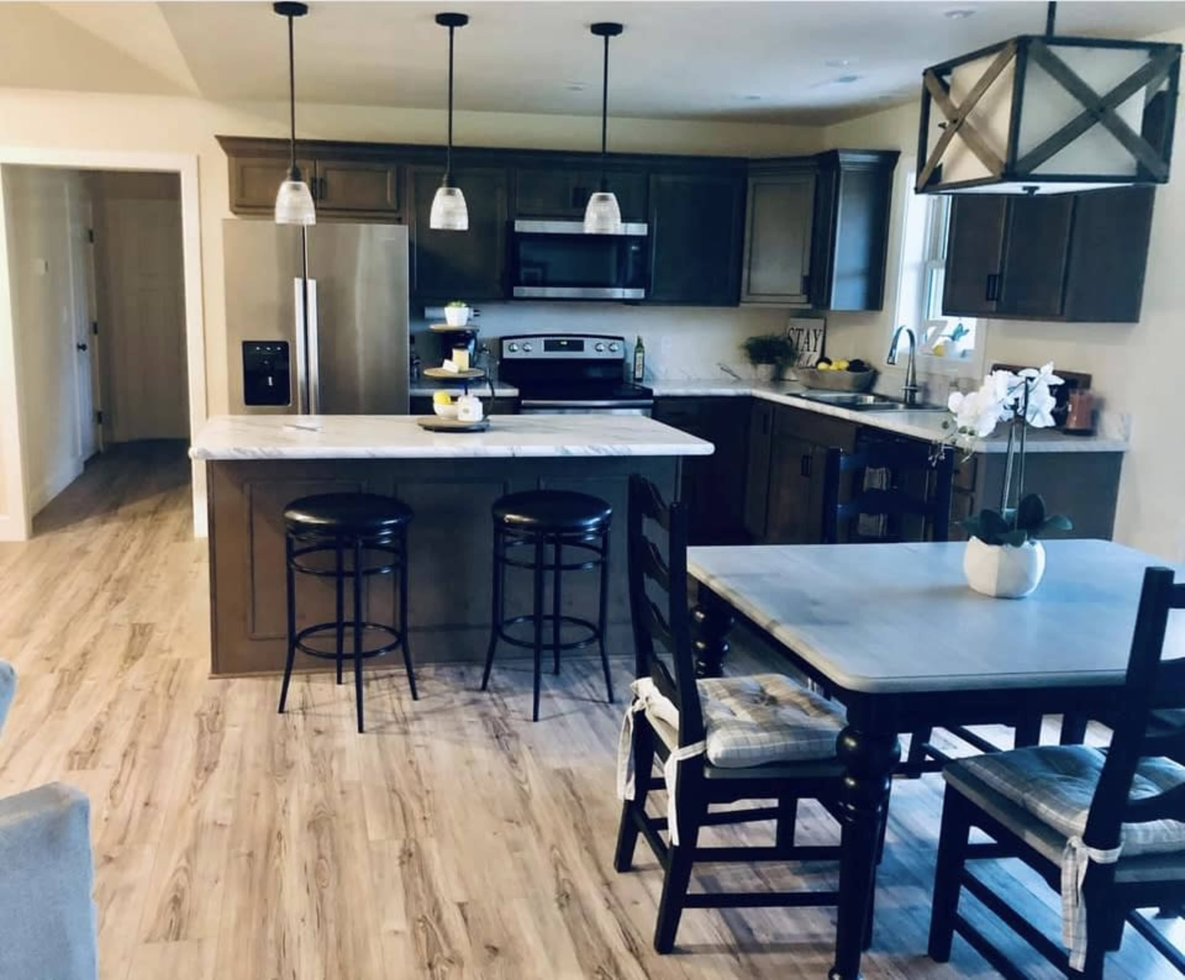 A modern kitchen with dark cabinetry, a large island with seating, and a dining table set for meals.