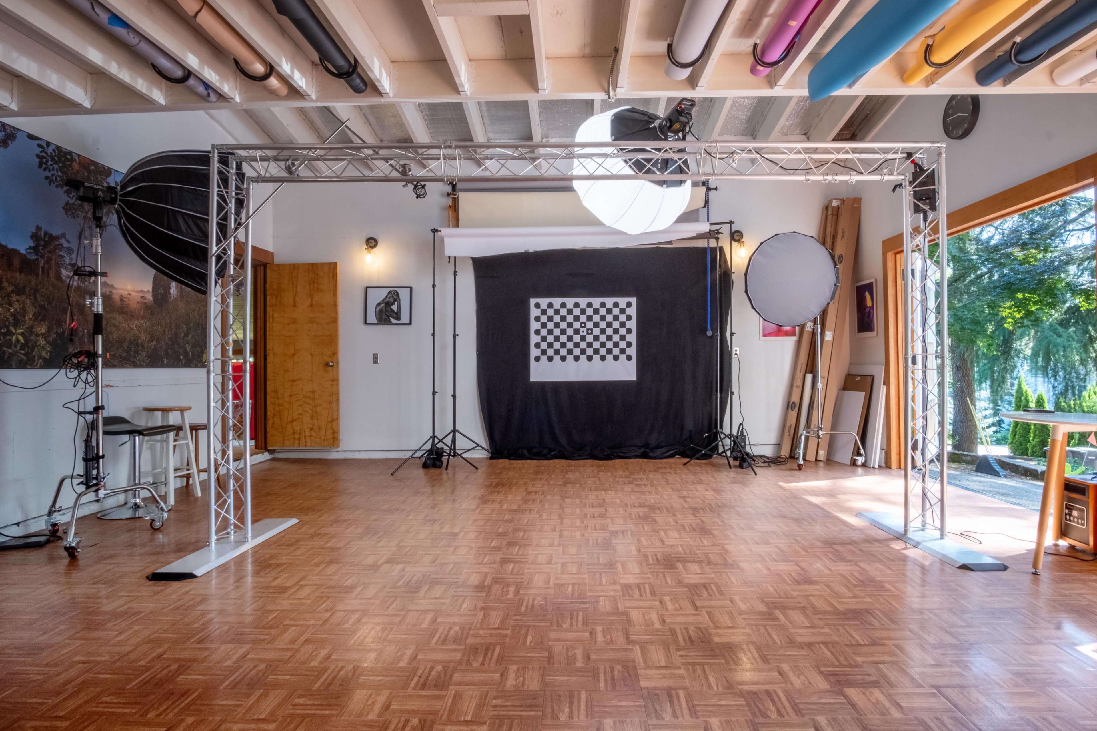 A photography studio setup featuring a checkerboard backdrop, lighting equipment, and a wooden floor.