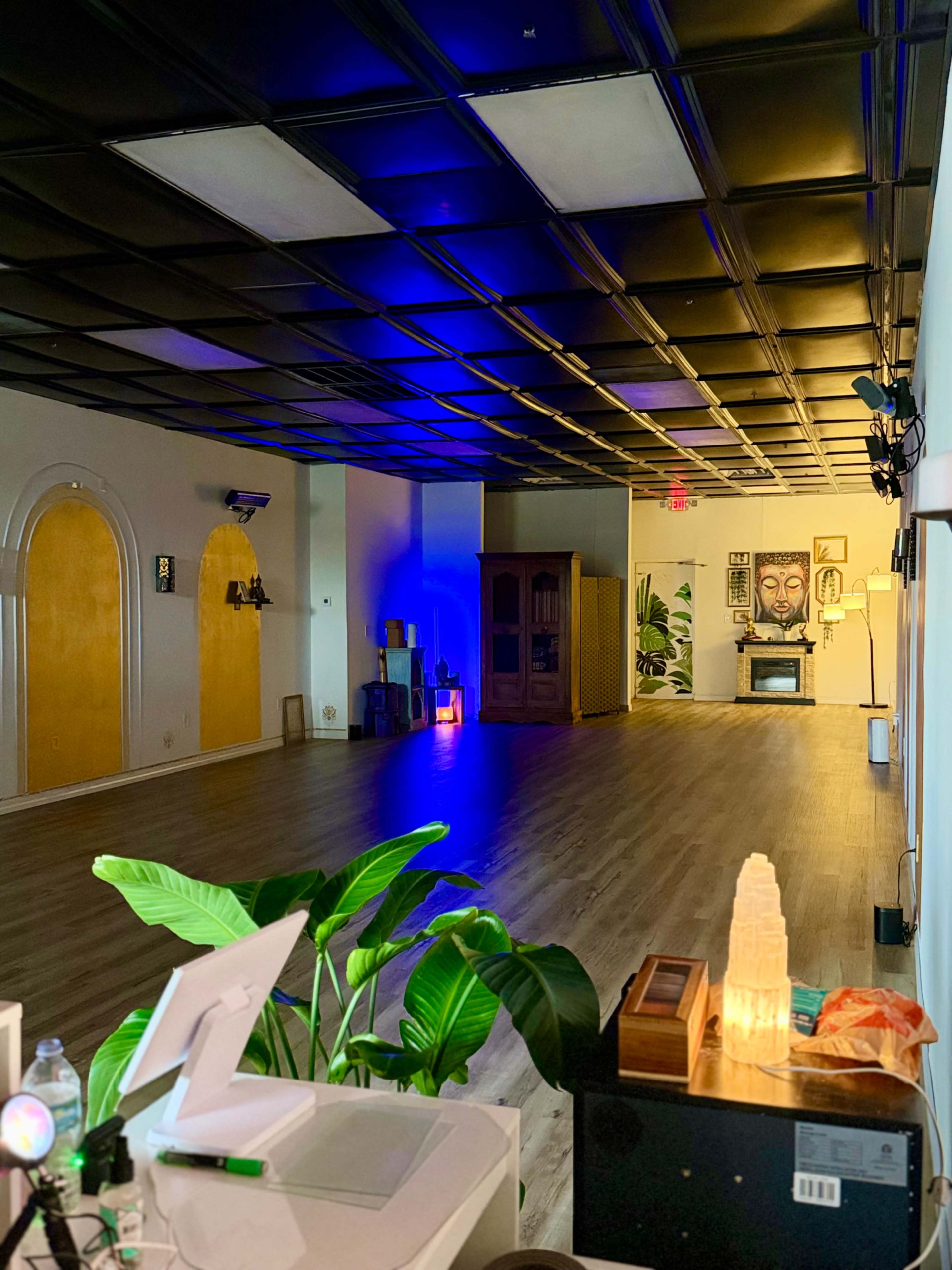 The image shows a spacious interior of a room with wooden flooring, colorful lighting, and various decorative elements along the walls.